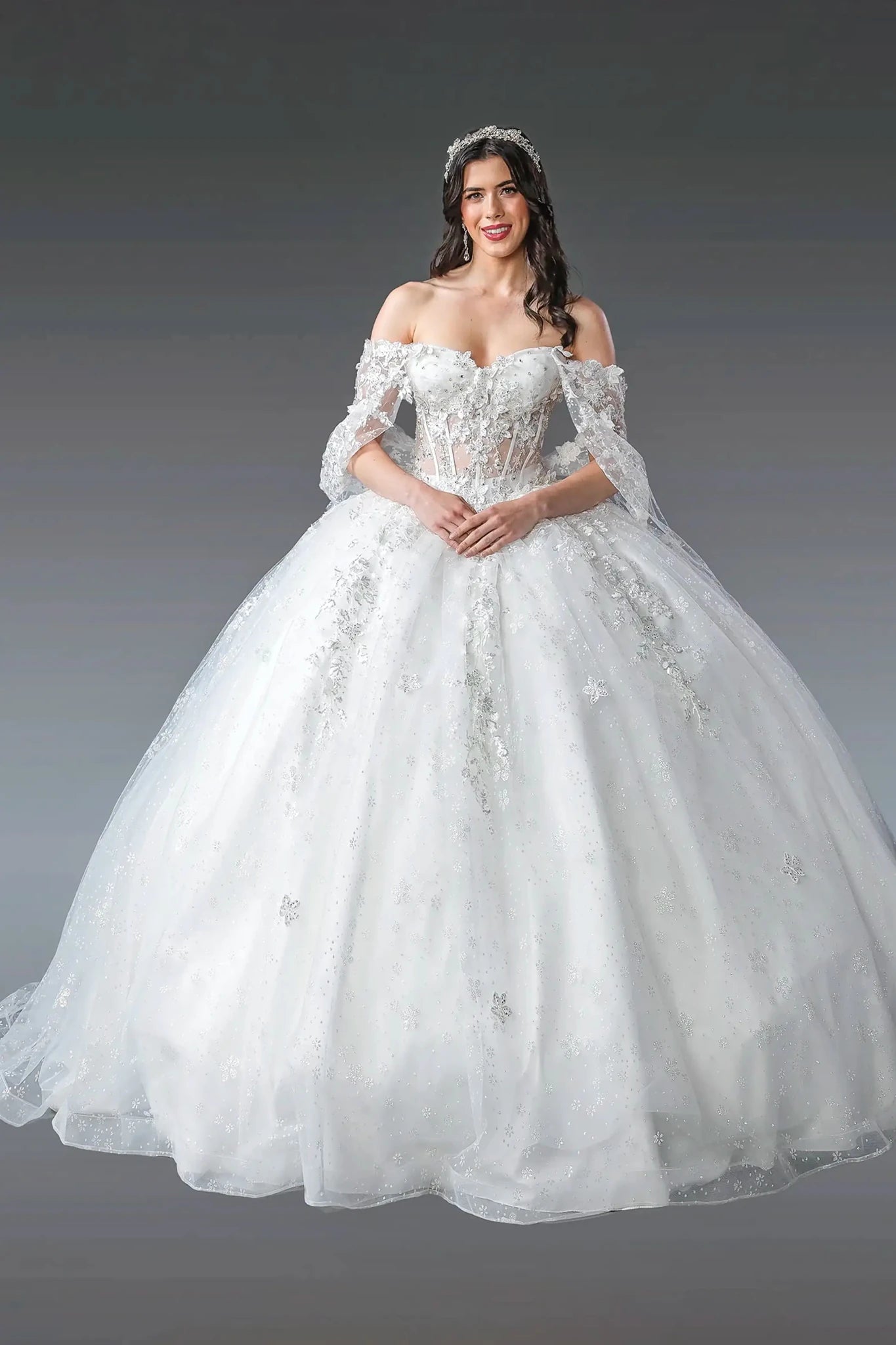 Woman in a white ball gown dress with floral details on a gray background