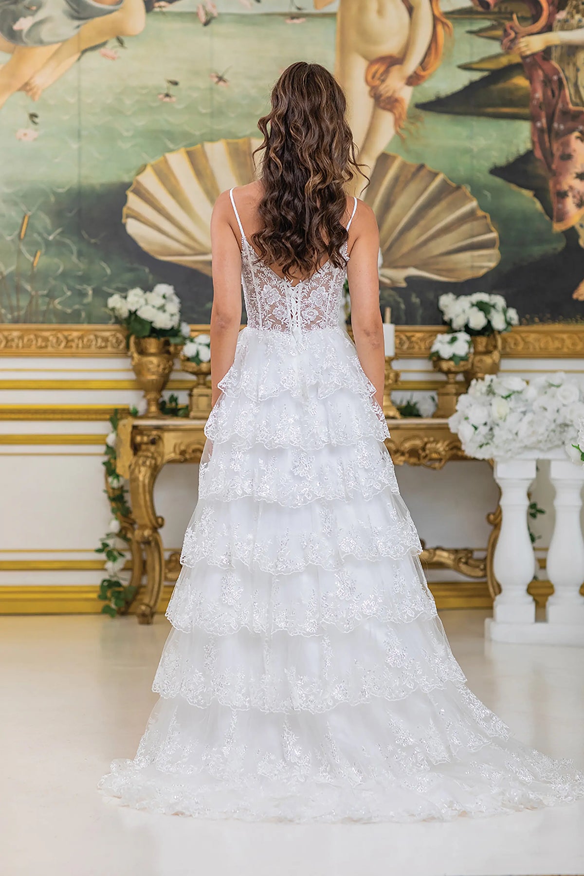 Revealing layered lace ruffles flowing into a train, this Off-White wedding dress is shown from the back.