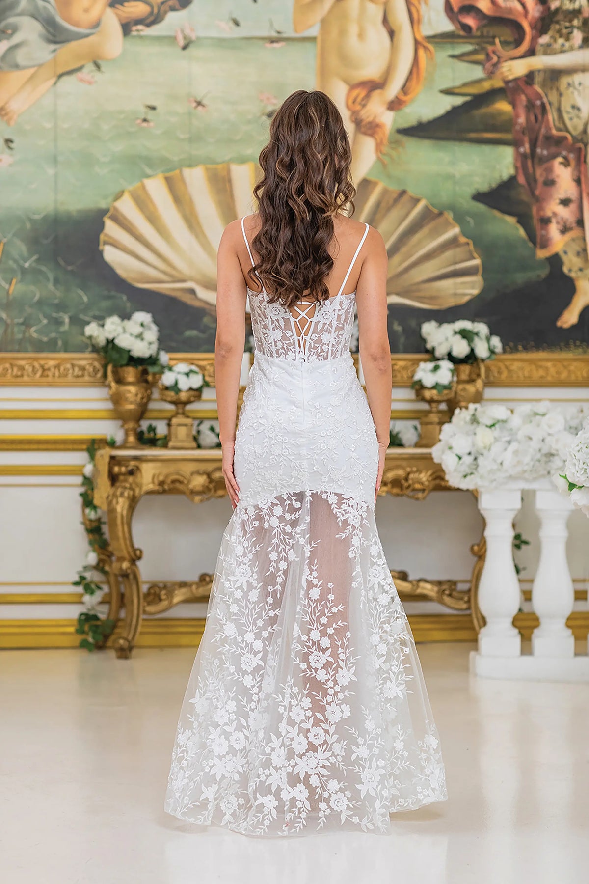 Revealing sheer lace detailing and a softly trailing hem, this Off-White wedding dress is shown from the back.