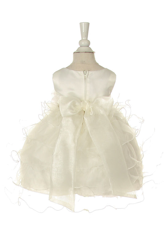 Back view of Little girl wearing ivory rose dress at wedding or christening event posing elegantly