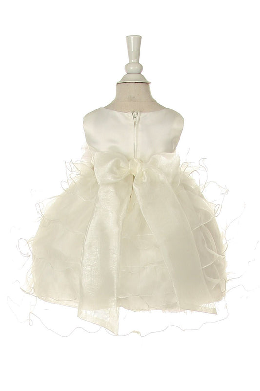 Back view of Little girl wearing ivory rose dress at wedding or christening event posing elegantly
