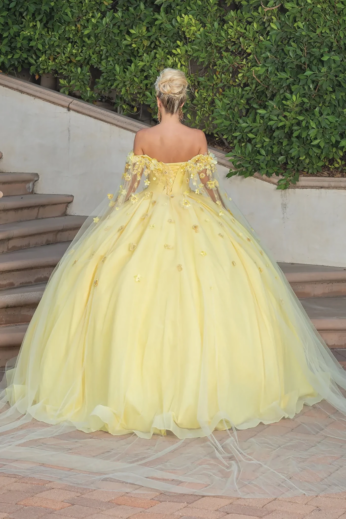 ellow off-the-shoulder ball gown with floral appliqué and a long sheer cape