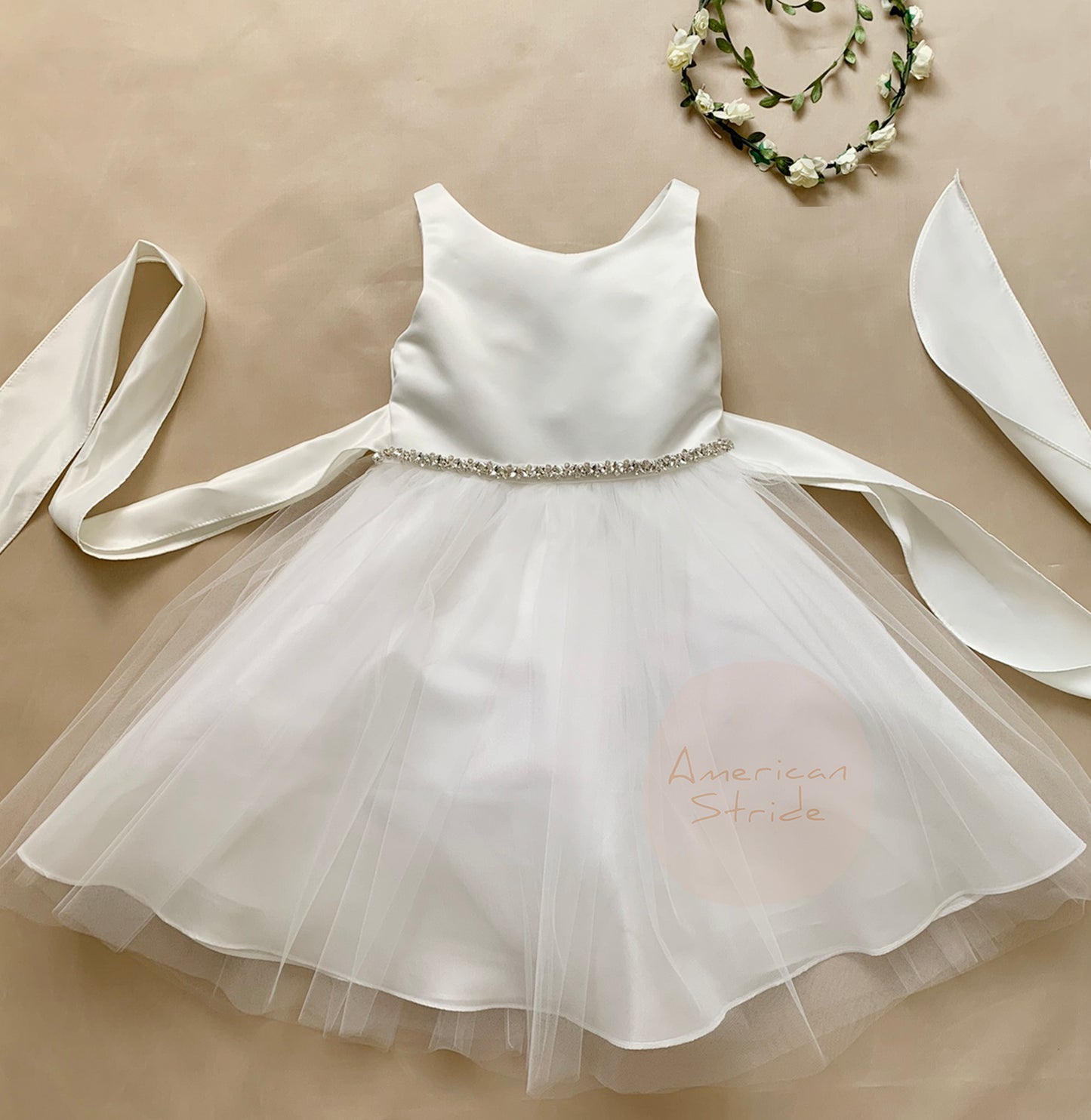 White children's flower girl dress with a decorative belt and ribbons.