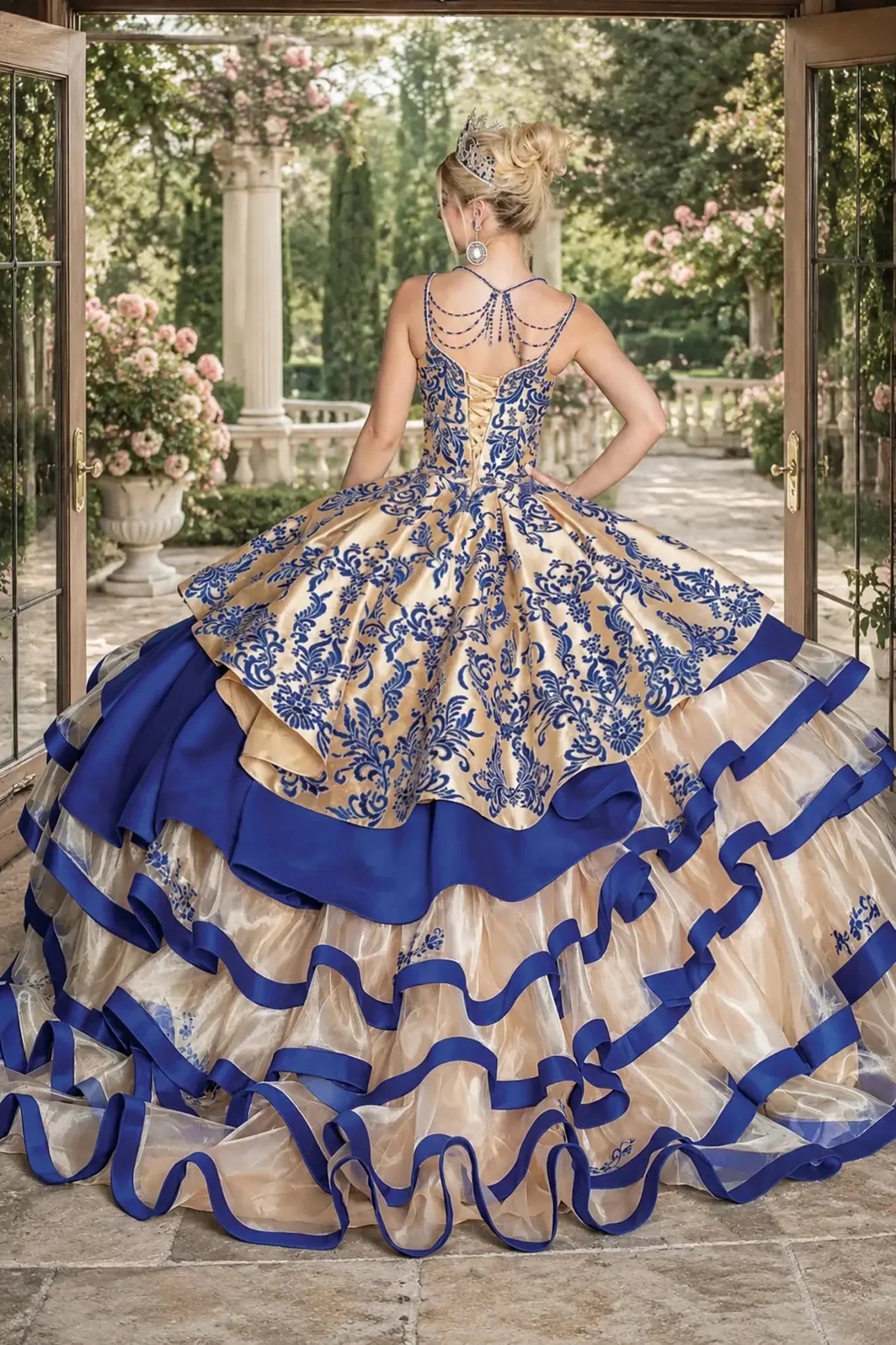 Back view of a gold and royal blue quinceanera dress with lace-up corset, embroidered bodice, and tiered ribbon-trimmed sheer skirt