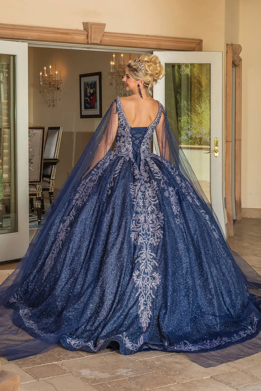 Back view of a woman wearing navy quinceañera gown, cape sleeves, corset Back, embroidery, glitter tulle