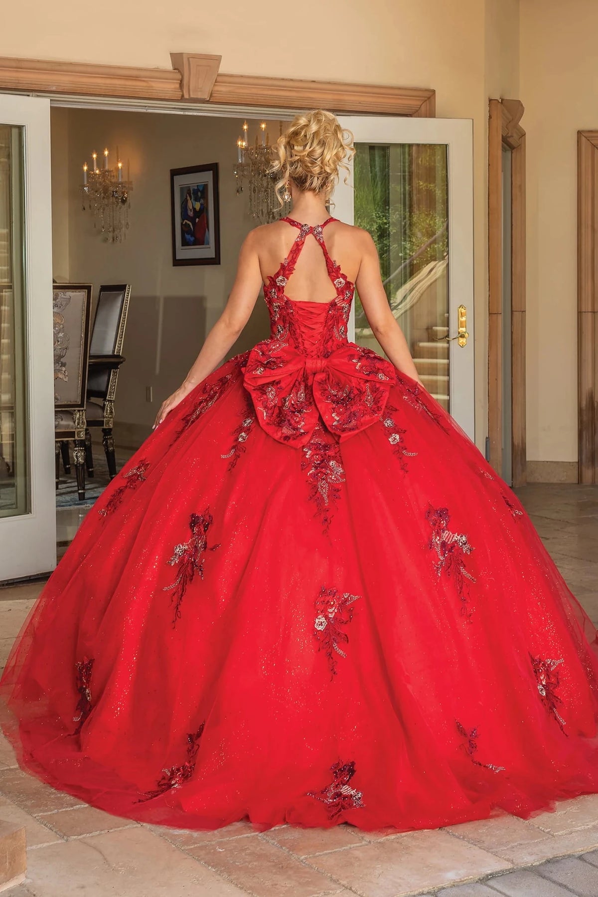Back view of a Red quinceañera gown showing lace-up back, ruffled layered skirt, and floral embroidery