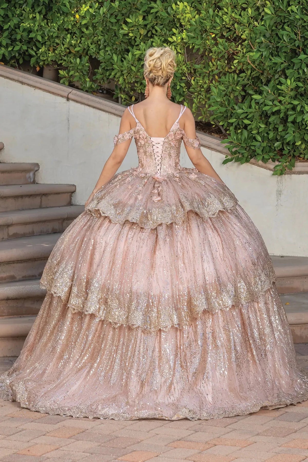 Back view of a Rose Gold quinceañera gown showing lace-up back, cap sleeves, and sequined tiered skirt