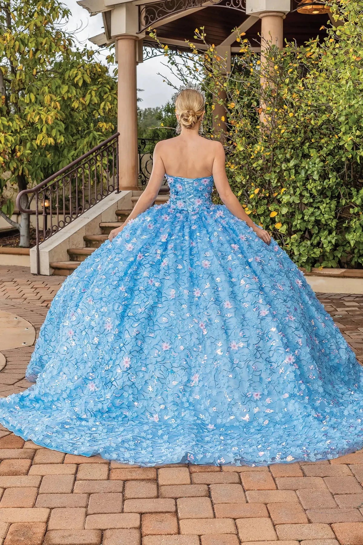 Back view of a Bahama Blue quinceañera gown showing lace-up back, layered tulle skirt, and floral embroidery