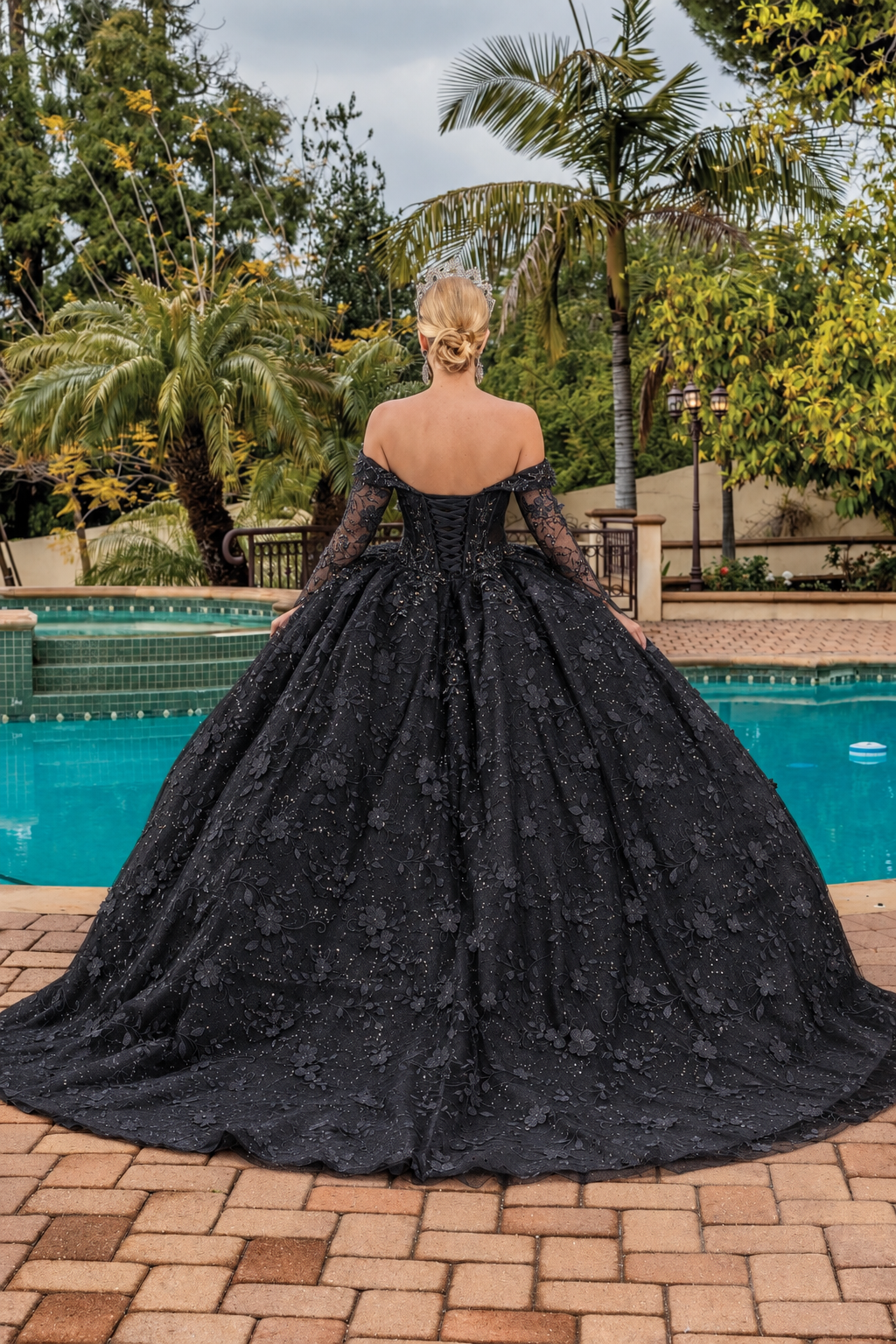 Back view of a Black quinceañera gown showing lace-up back, long sleeves, and floral appliqués