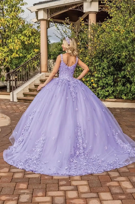Back view of a lilac quinceañera ball gown featuring a fitted corset back, floral appliqué details, flowing tulle skirt with soft train, and elegant outdoor venue backdrop.