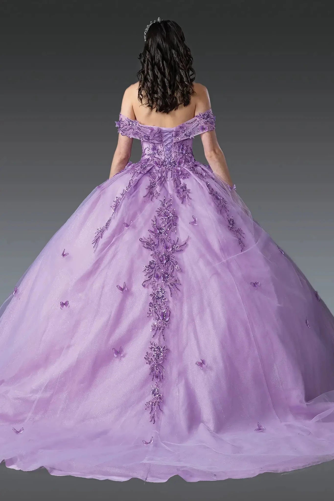 Back view of lilac off-shoulder quinceañera ball gown with lace-up corset back, floral appliqués, butterfly details, and voluminous layered tulle skirt