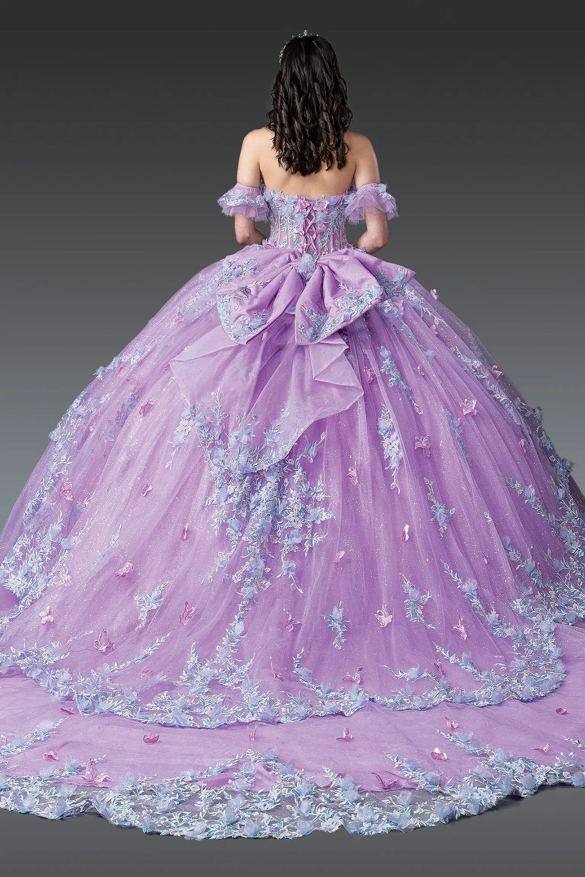 Back view of a Lilac quinceañera gown showing lace-up back, ruffled layered skirt, and floral embroidery