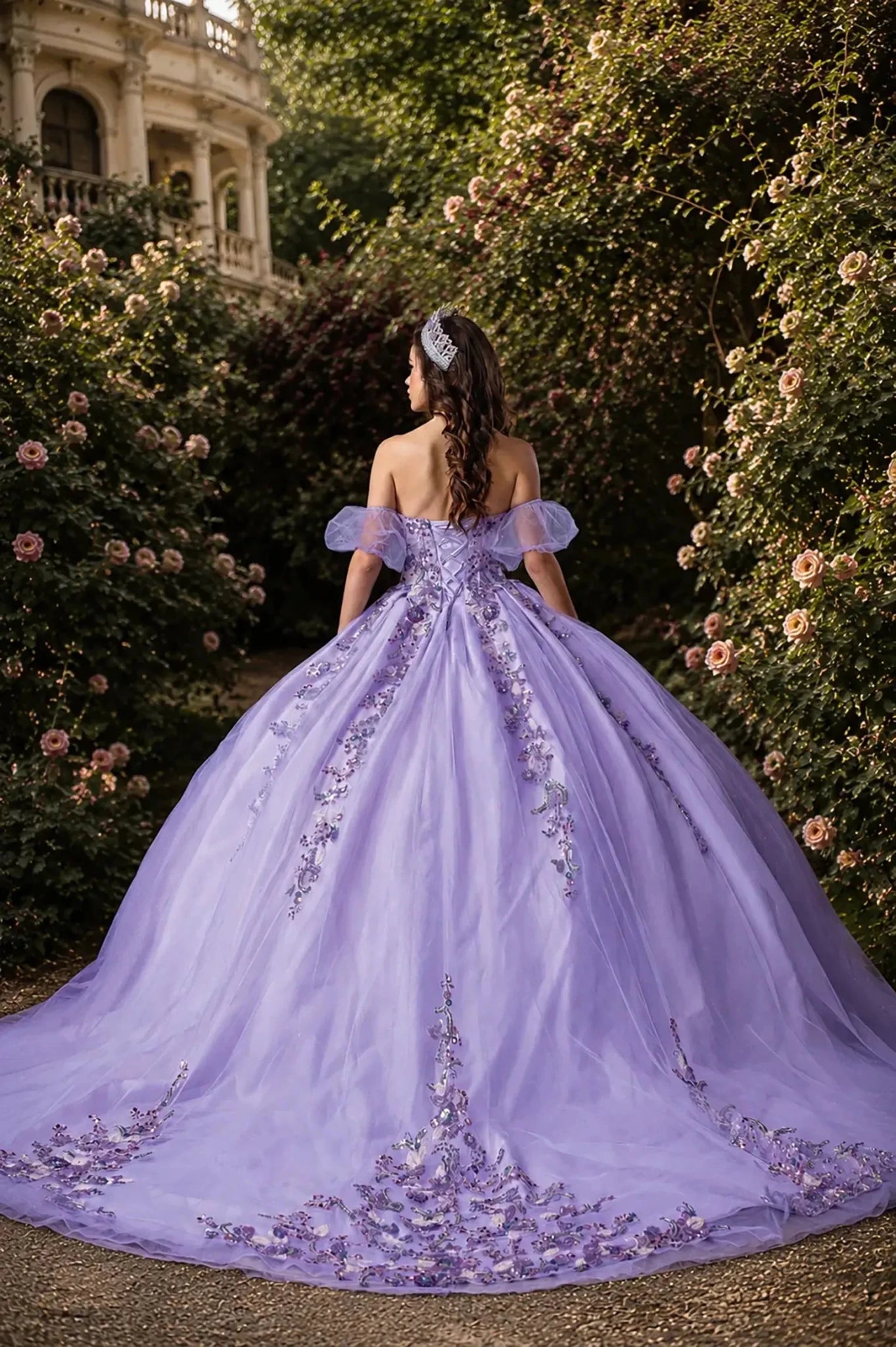 Back view of a lilac quinceanera dress with lace-up corset, floral appliques, glittered fabric, and long train