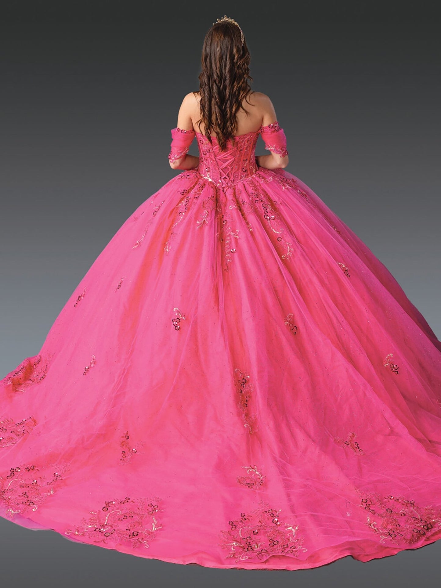 Back view of a woman wearing fuchsia quinceañera dress with lace-up corset, beaded embroidery and floral appliques