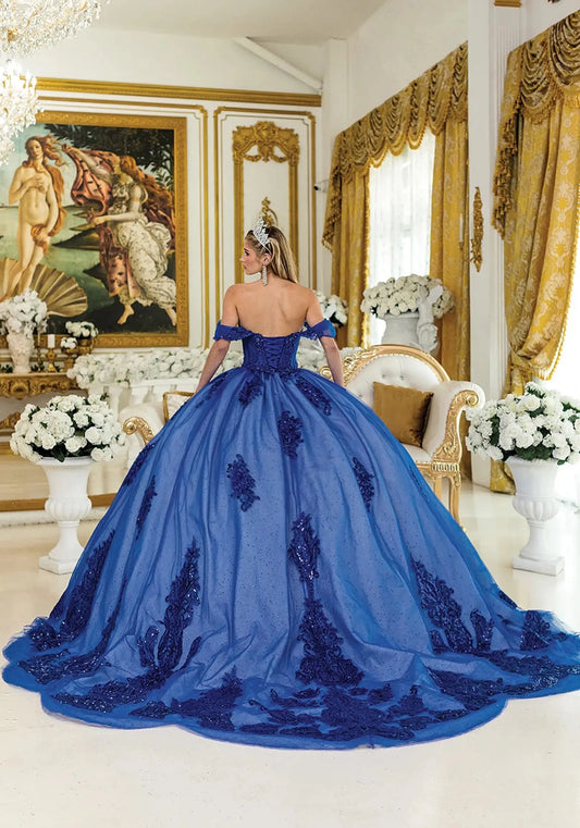 Woman in a blue ball gown with long train standing in an elegant room with gold accents and classical art.