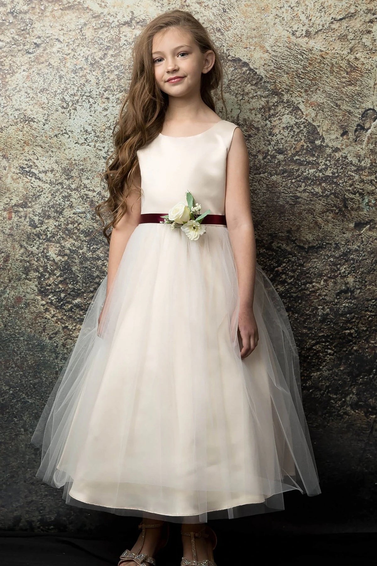 Detailed view highlights a champagne flower girl dress with a red belt.