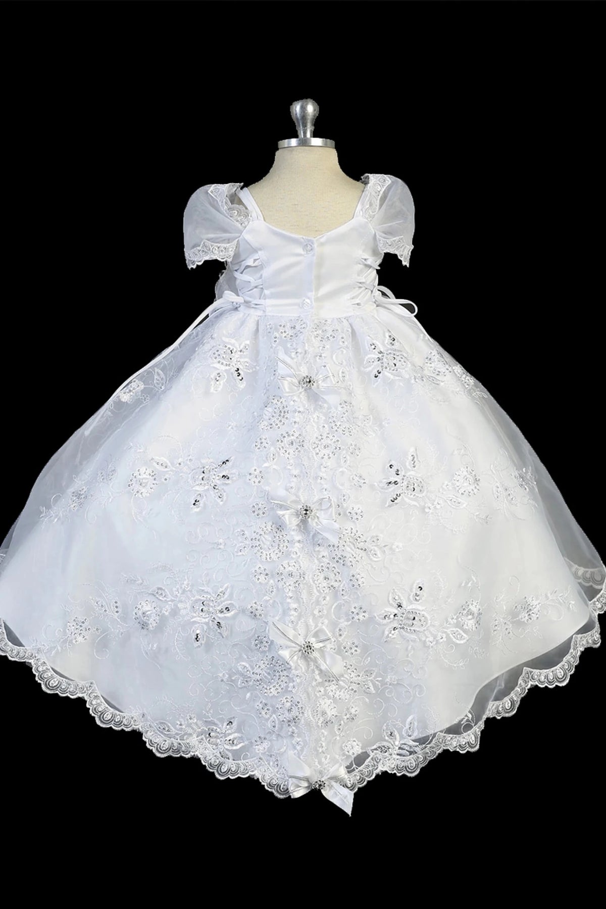 Detail of the white baptism dress showing Virgin Mary embroidery on the split organza skirt.