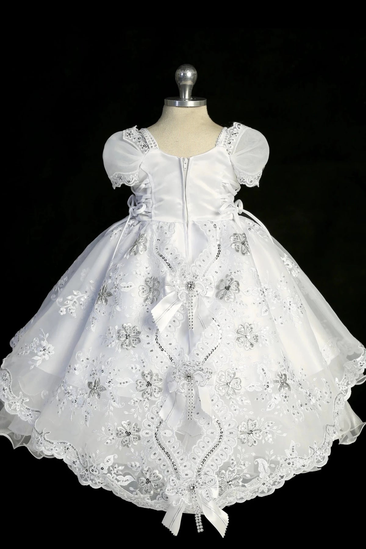 Detail of the white baptism dress showing Virgin Mary embroidery on the split organza skirt.