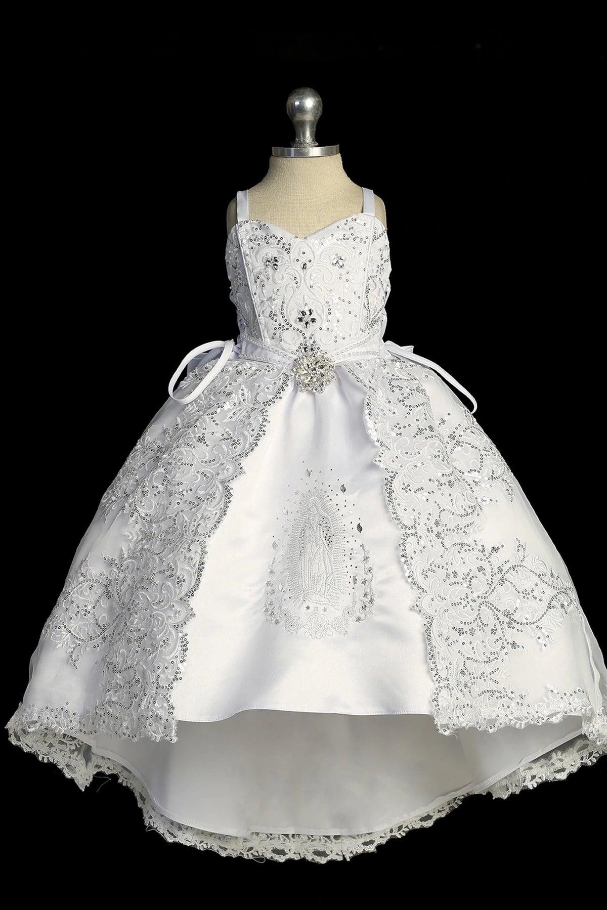 Detail of the white baptism dress showing high-low skirt with Virgin Mary embroidery and bow accents.