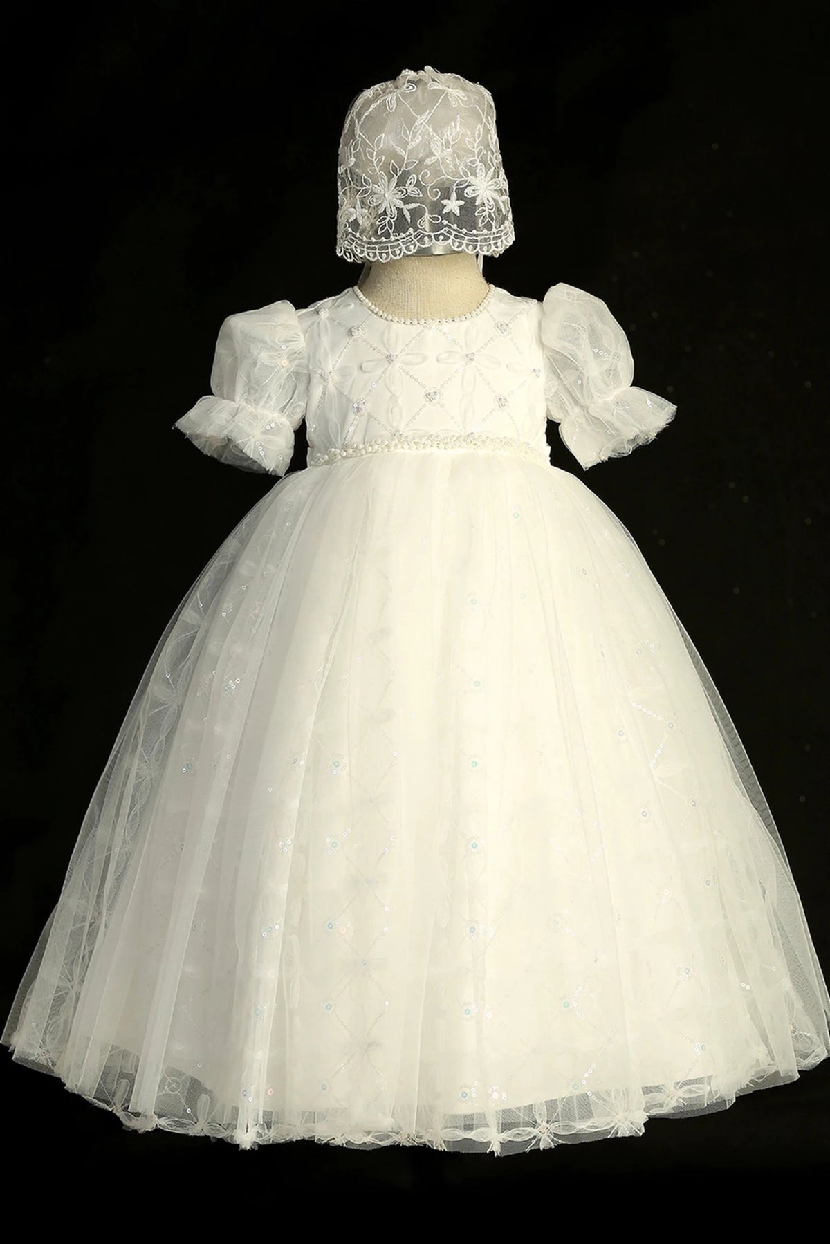Detail of the ivory christening dress showing mesh overlay skirt with sequins and braided pearl detail.