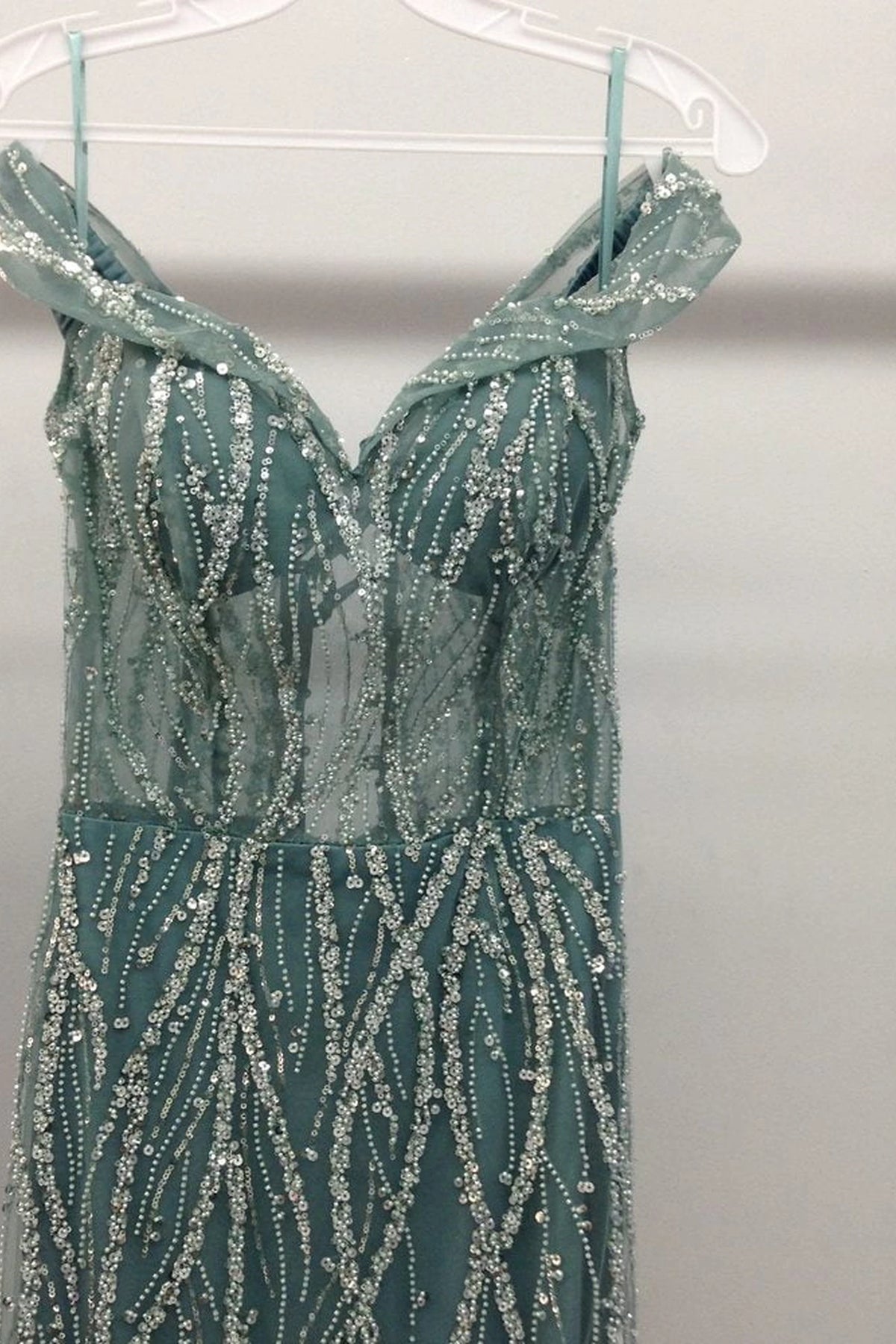 Showing its fabric texture, the Sage prom dress highlights the garment construction.