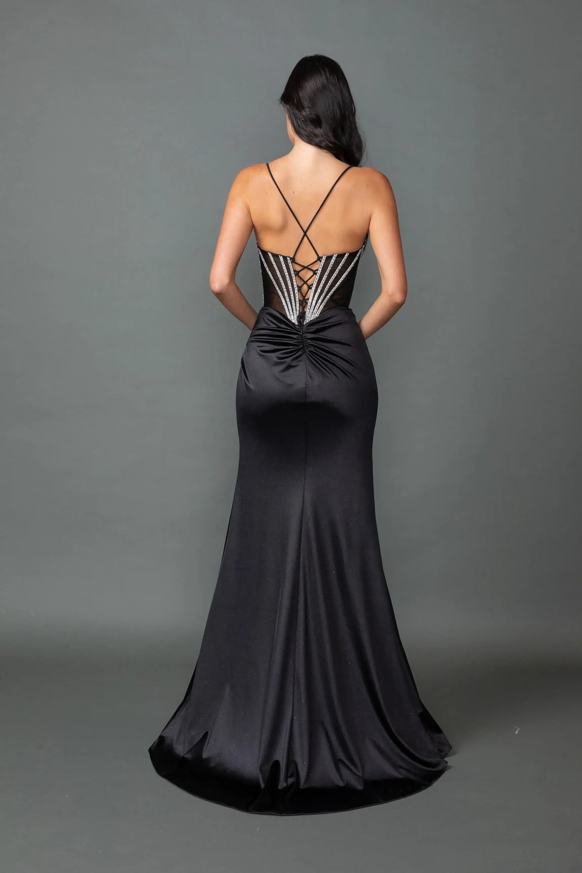Revealing crisscross straps above its satin skirt, this Black prom dress is shown from the back.