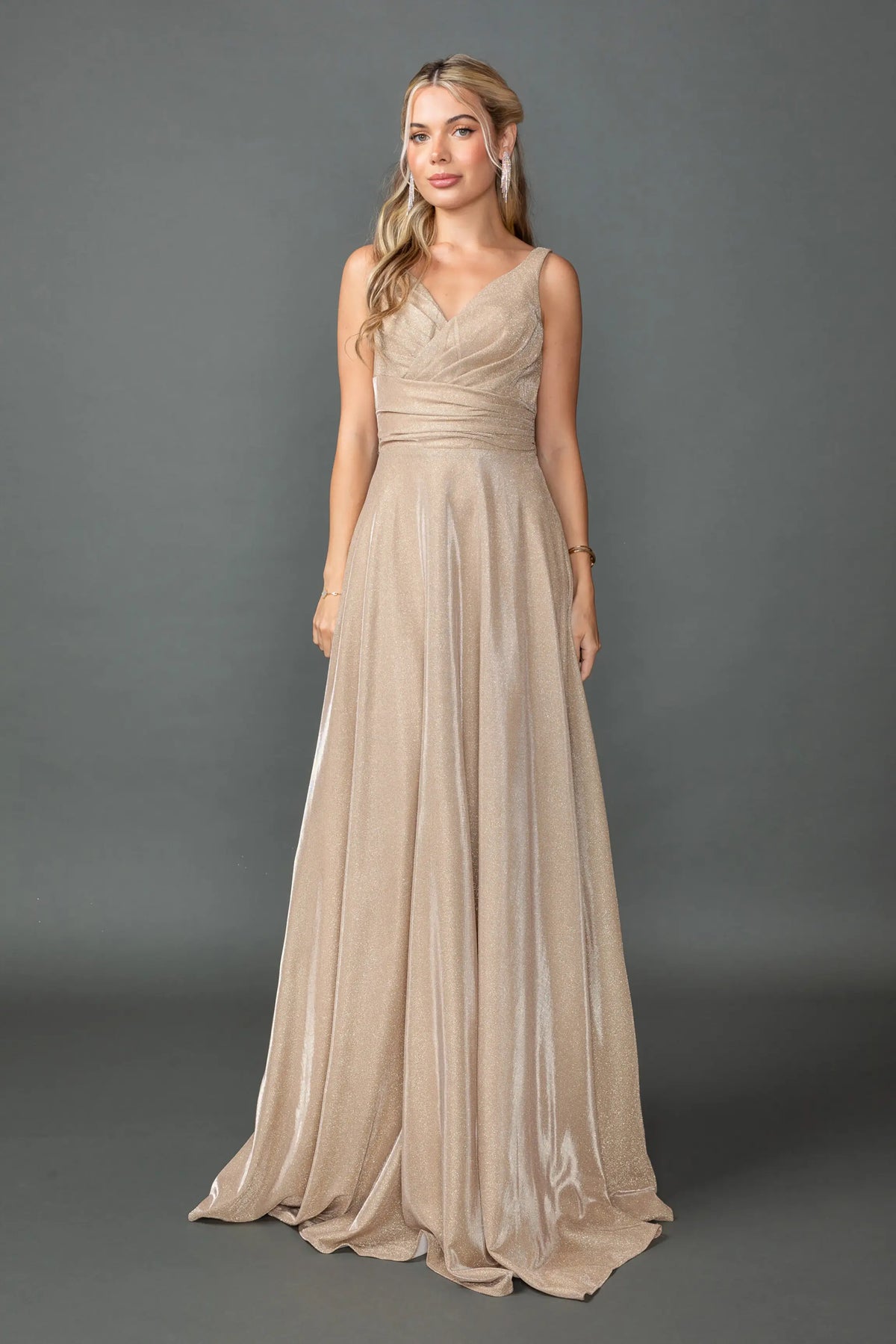 Showing a ruched V-neck bodice and flowing glitter skirt, this Champagne prom dress is shown in full view.
