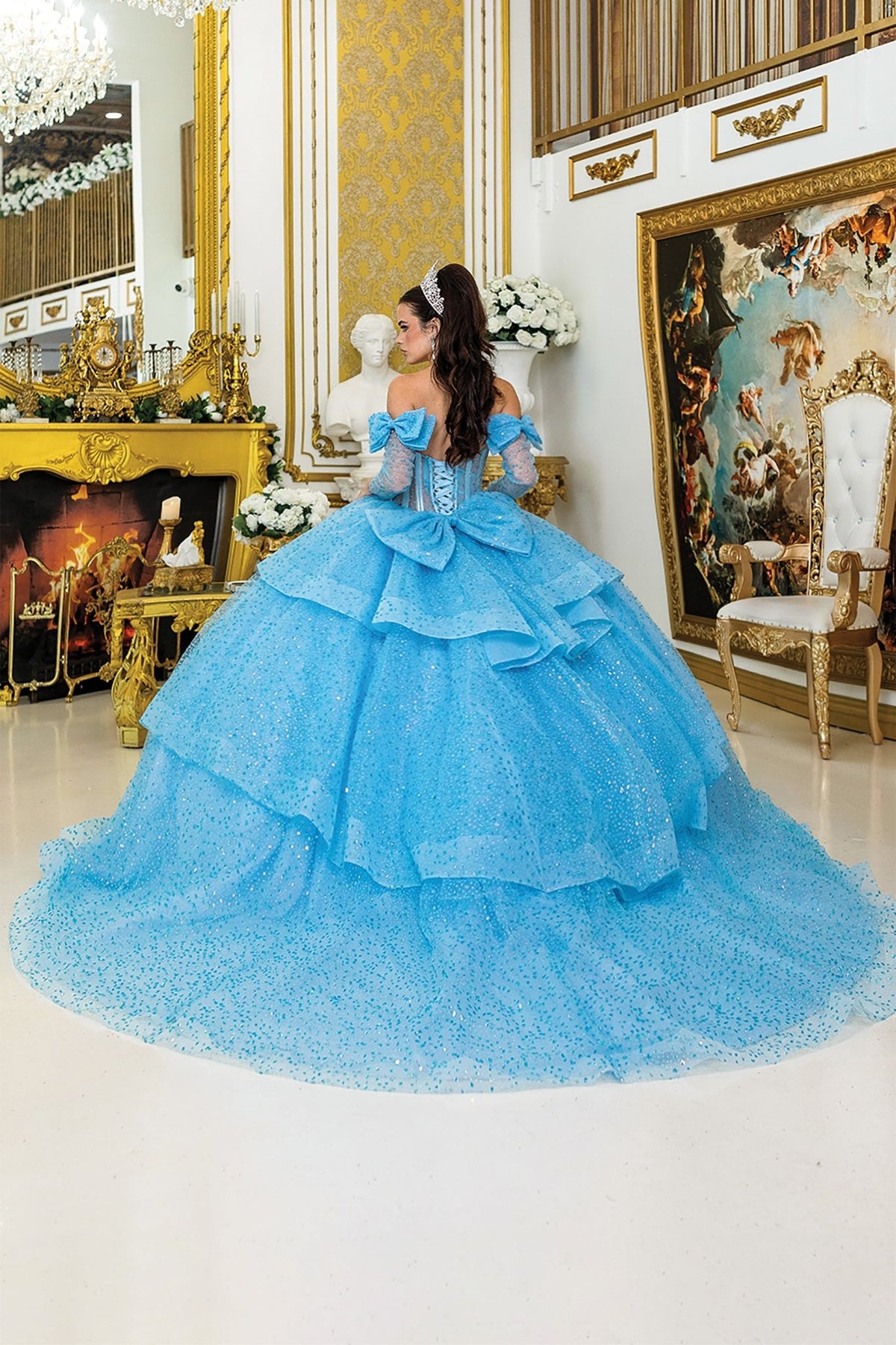 Back view of a woman wearing bahama blue quinceañera dress with lace-up corset, detachable sleeves and layered tulle skirt