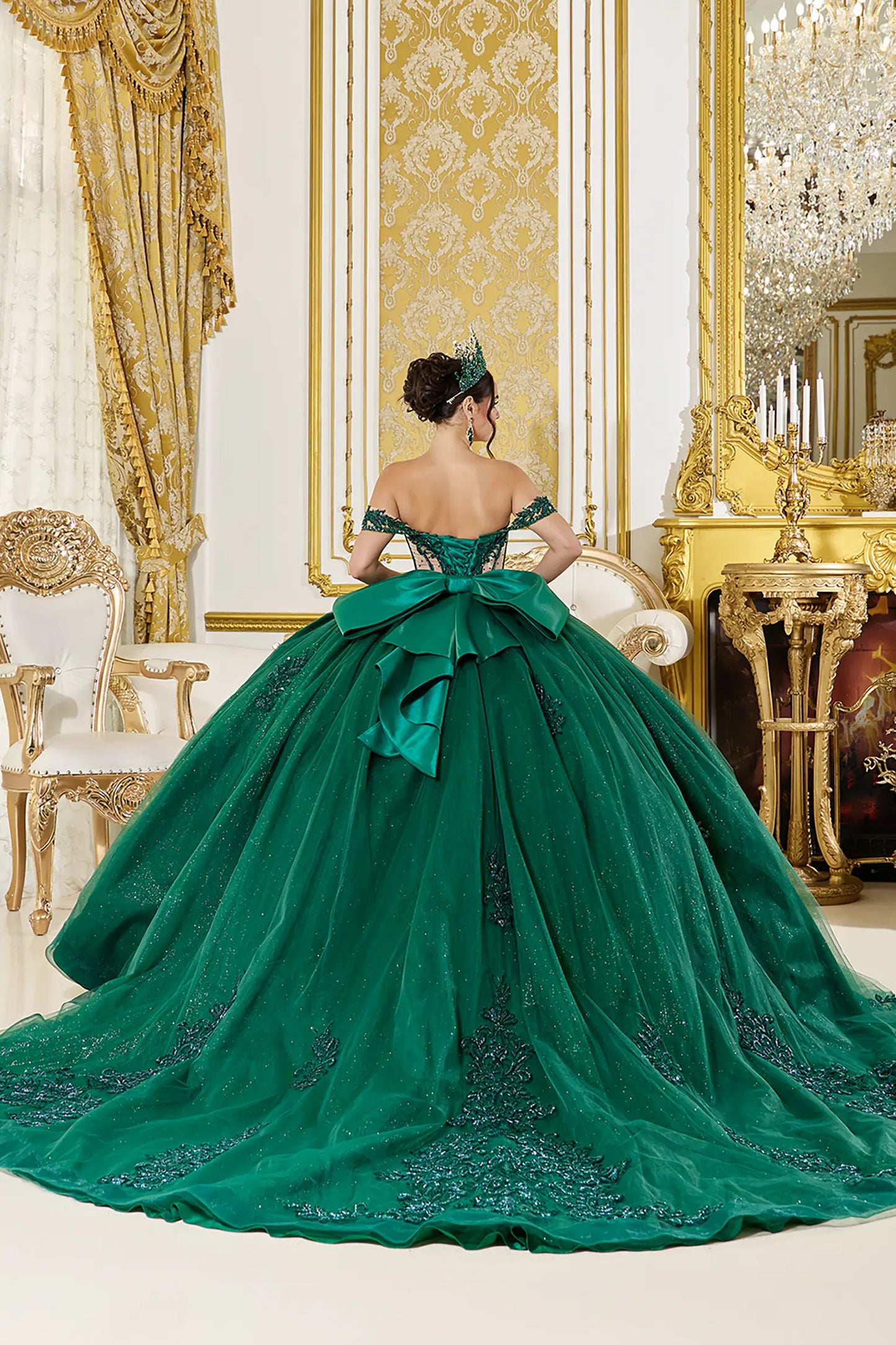 Back view: Emerald green quinceañera ball gown back view featuring a lace-up corset, dramatic oversized bow, intricate lace appliqués, and a voluminous tulle skirt with soft train