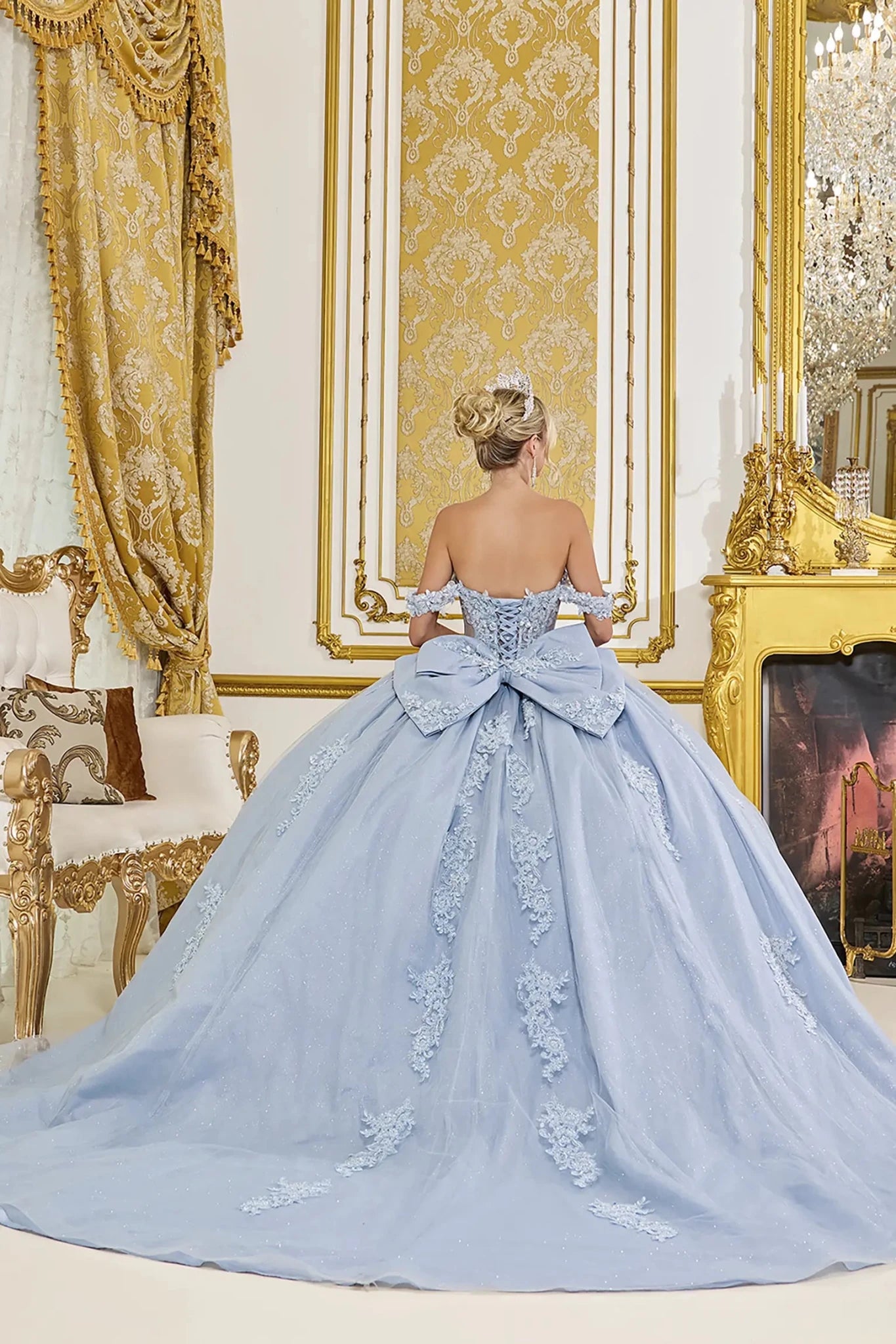 Dusty blue quinceanera ball gown back view showing lace up corset back, oversized bow accent, embroidered tulle skirt, and flowing train