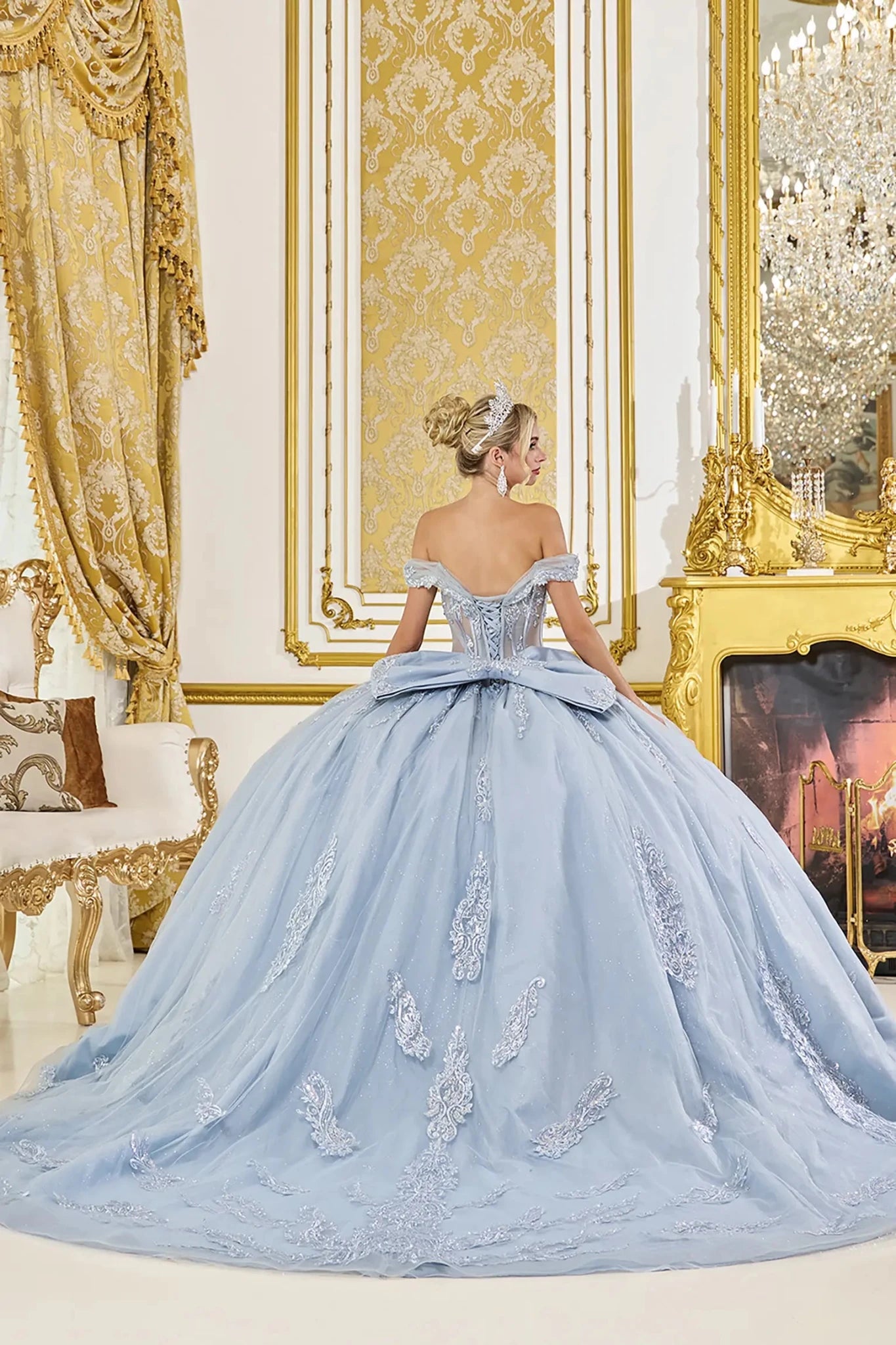 Dusty blue quinceanera ball gown back view showing lace up corset back, oversized bow accent, embroidered tulle skirt, and sweeping train