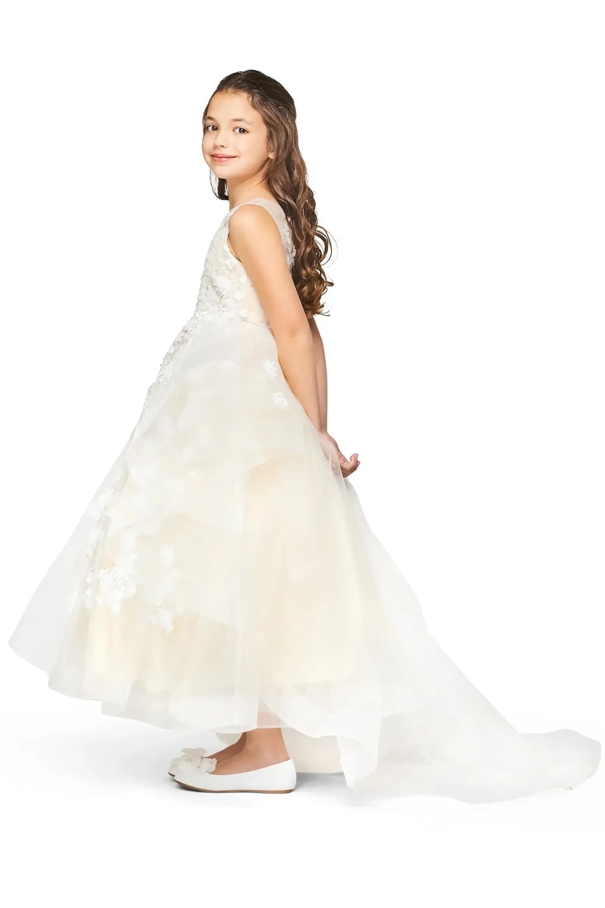 Side view of champagne high-low flower girl dress with lace appliqué detailing, shimmering sequin beads, and flowing detachable train.