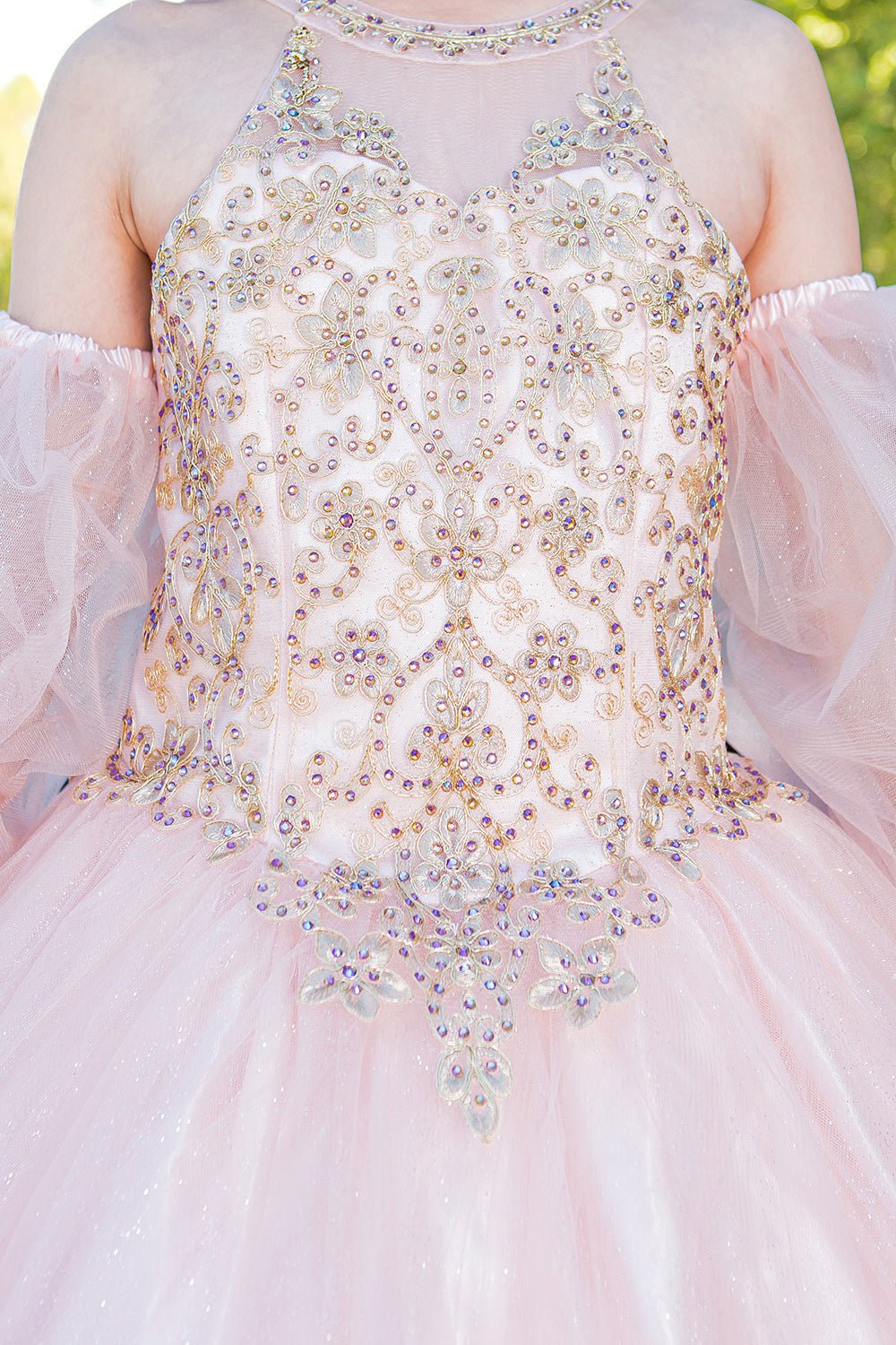 Close-up of blush mini quince dress with gold applique beading glitter tulle and layered sparkle accents