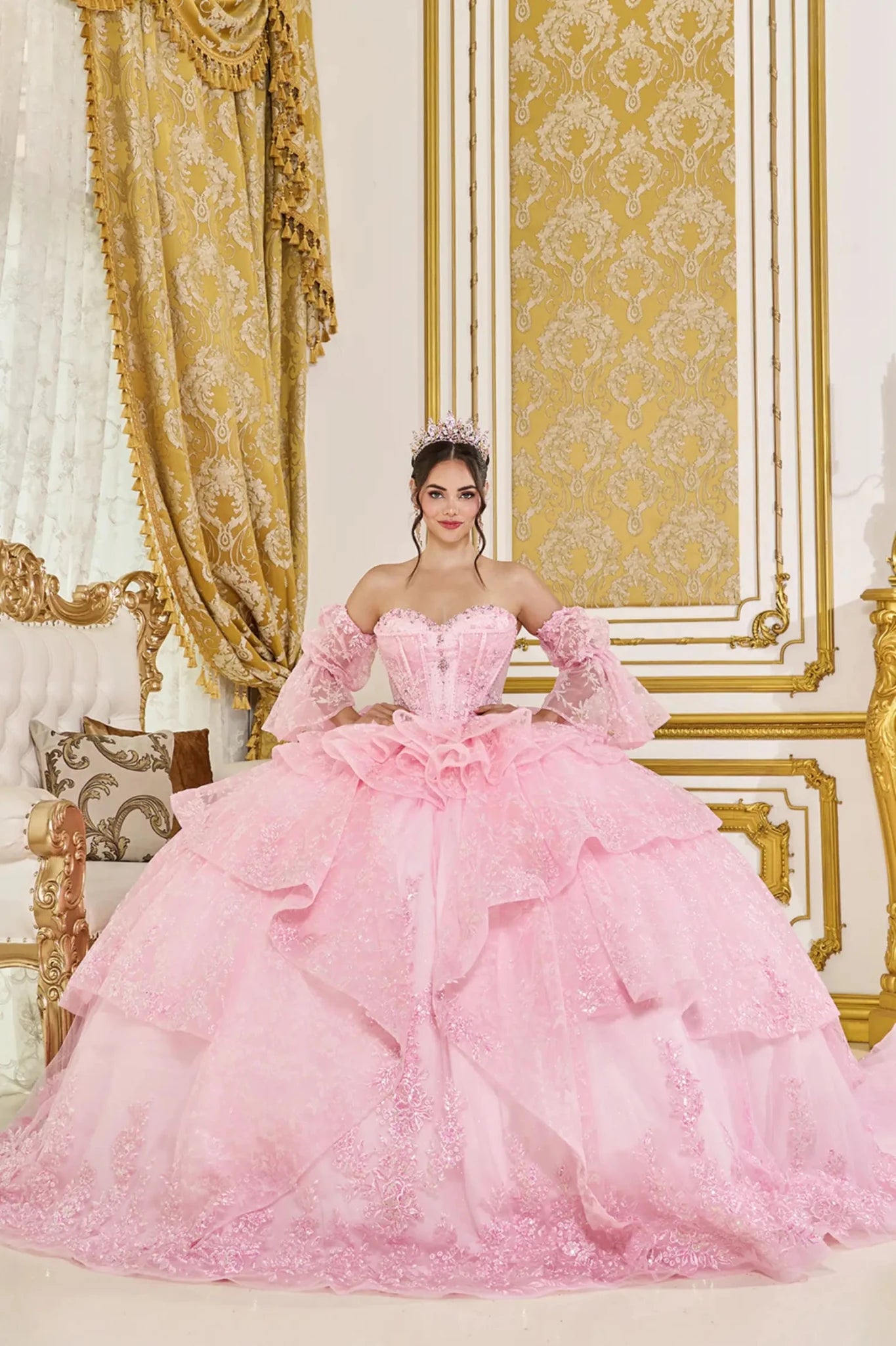 Front view of pink quinceañera ball gown with off-the-shoulder puff sleeves, sweetheart corset bodice, and layered glitter tulle skirt with ruffle details.