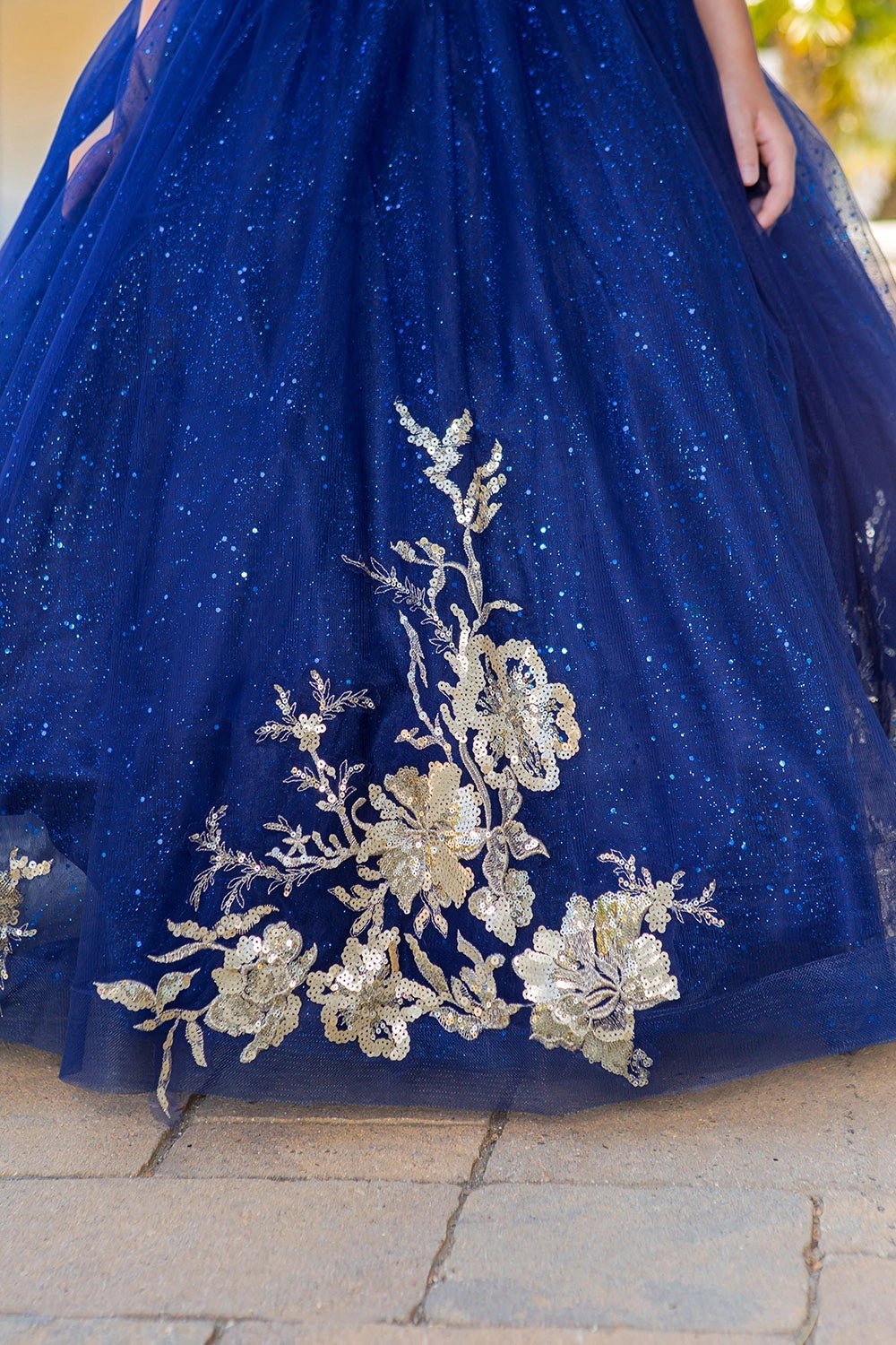 Shown in a skirt detail, the Navy mini quince dress has gold floral appliques along the glitter tulle hem.