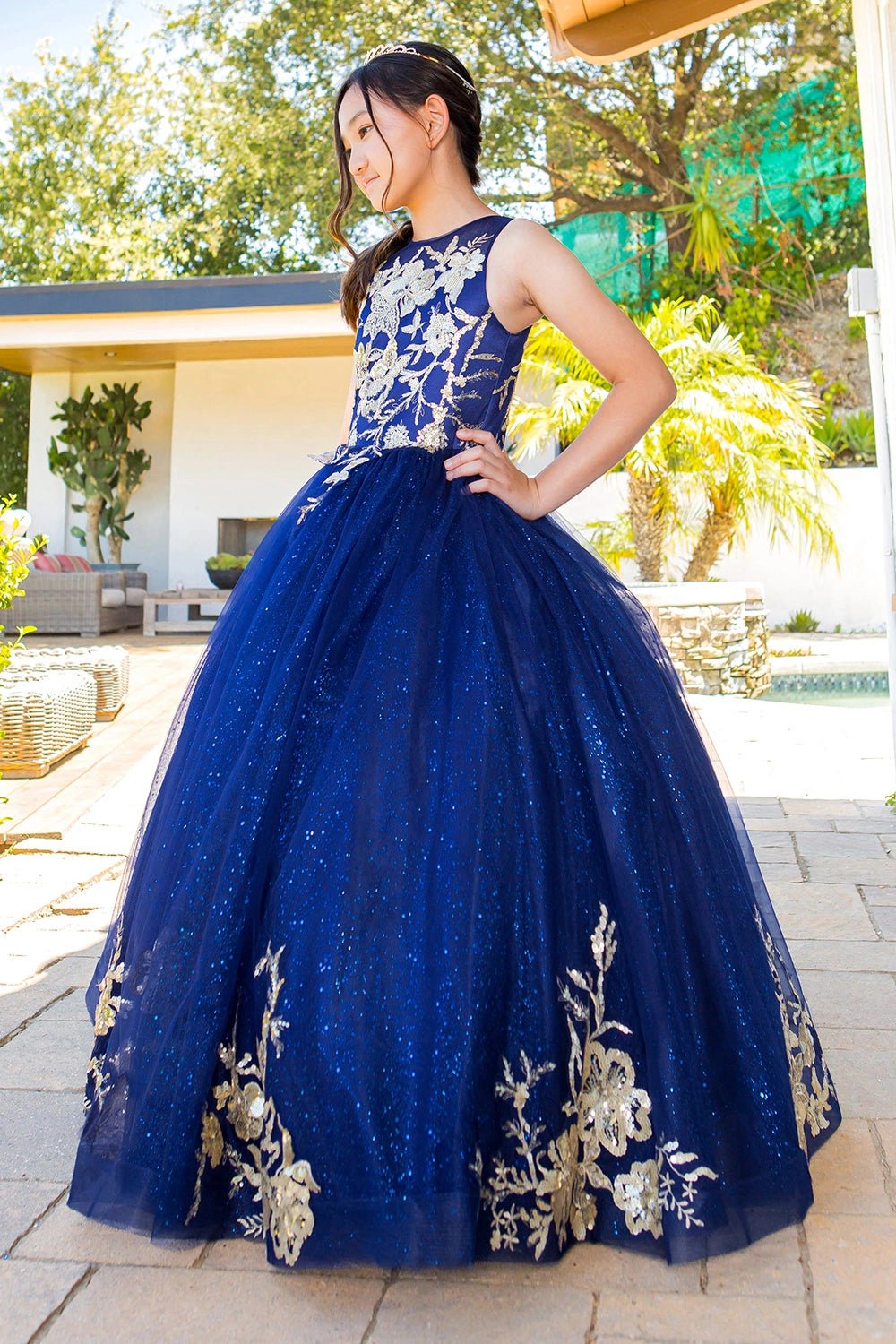 Displayed in a angled view, the Navy mini quince dress has sleeveless floral lace bodice and full glitter tulle skirt.