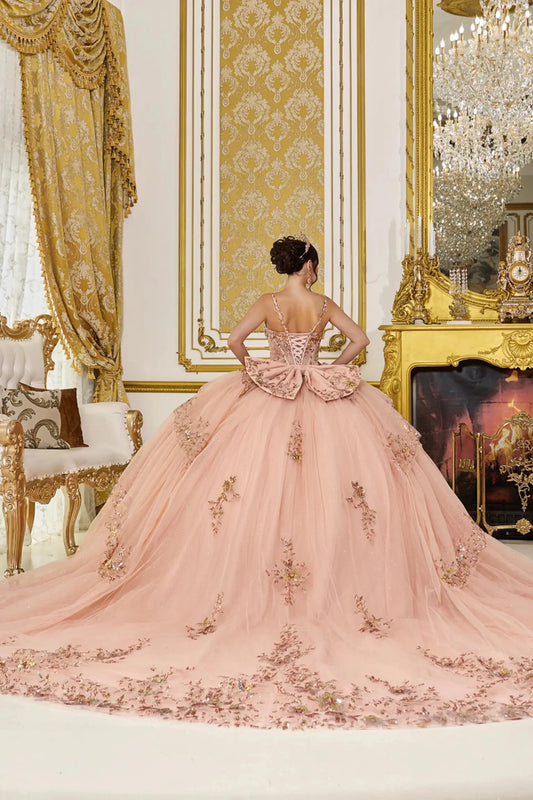 Back view of rose gold quinceañera ball gown showing lace-up corset back, oversized bow detail, and dramatic layered tulle skirt with embroidered floral appliqués.