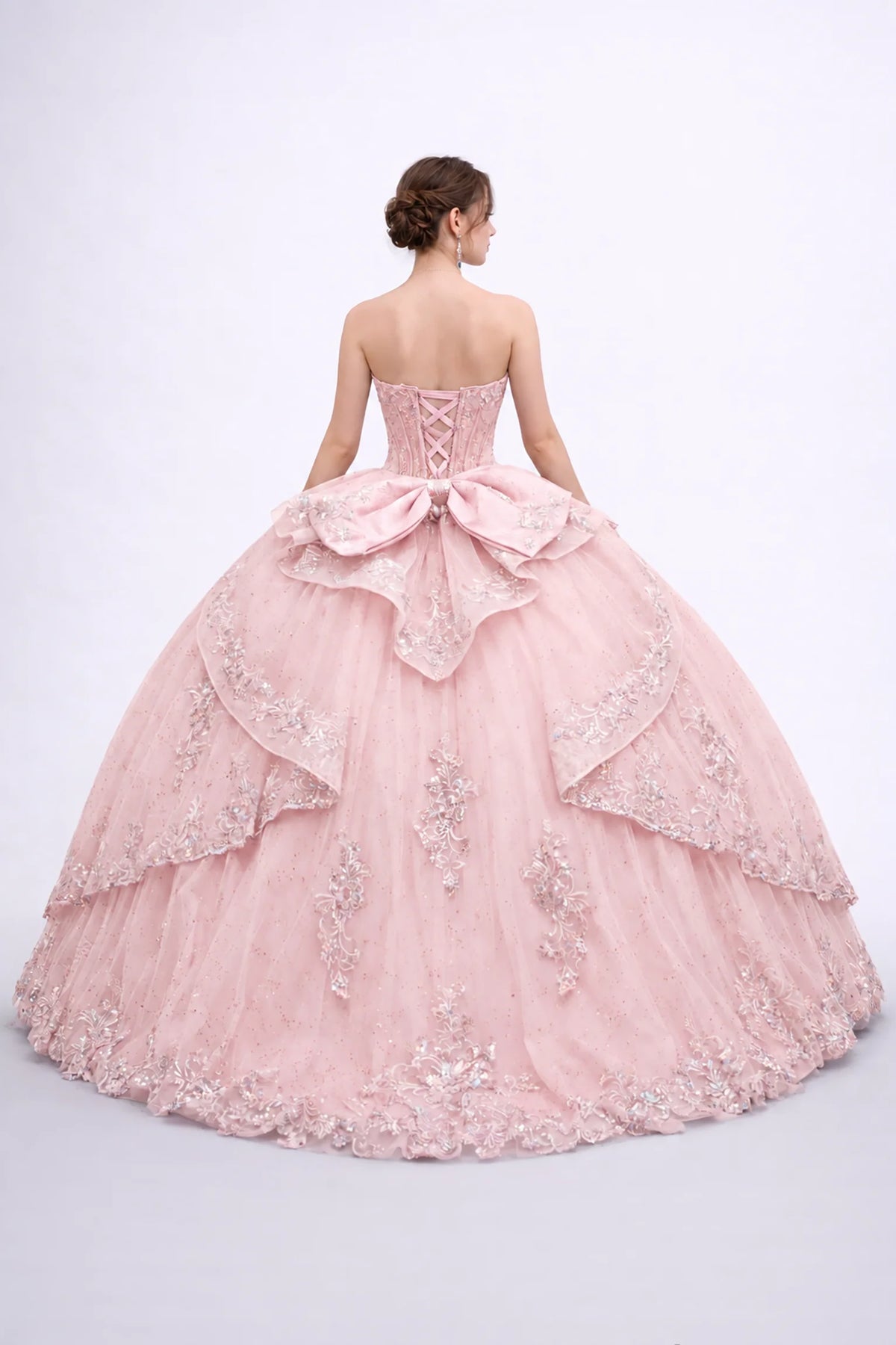 Back view of a Blush quinceañera dress showing a lace-up corset, oversized bow and embroidered layered tulle skirt