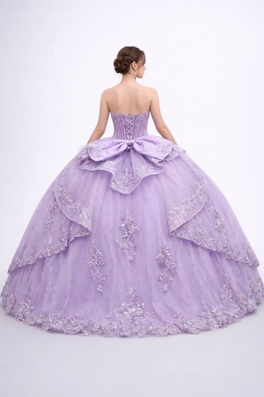 Full back view of a woman in a lilac quinceañera ball gown featuring lace-up corset back, cascading layered tulle overskirt, embroidered applique accents, and sparkling bead details