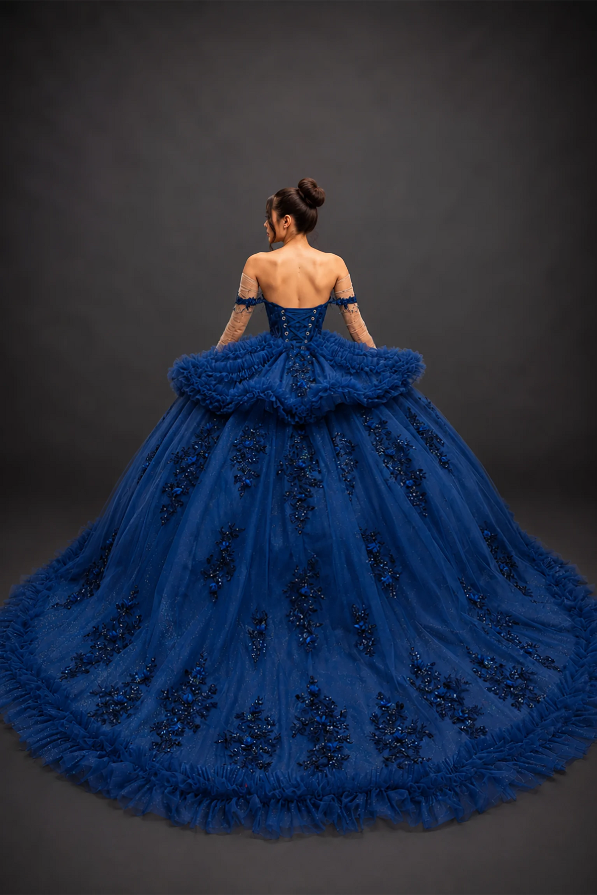 Back view of navy quinceañera dress with lace-up corset and tiered ruffle train