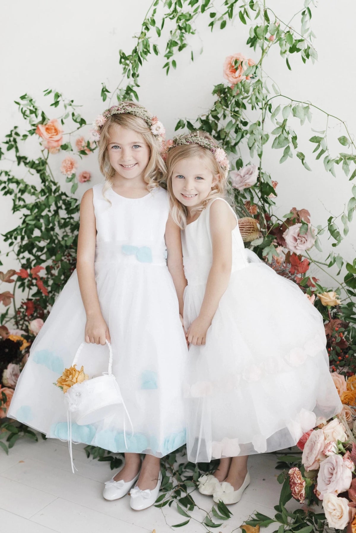 Pastel petals dot the hems of these white flower girl dresses.