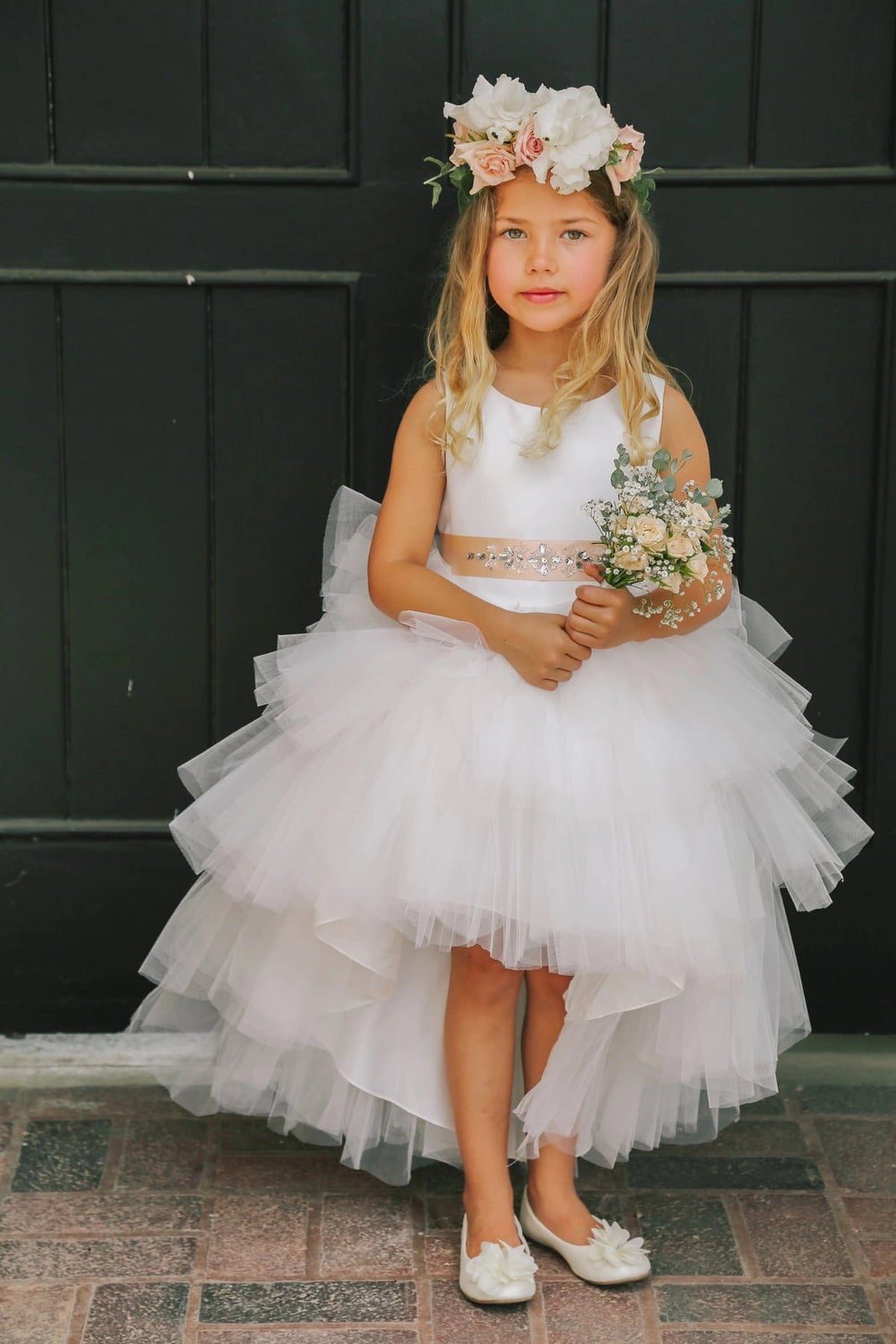 The White kids pageant dress has a satin bodice and layered high-low tulle.
