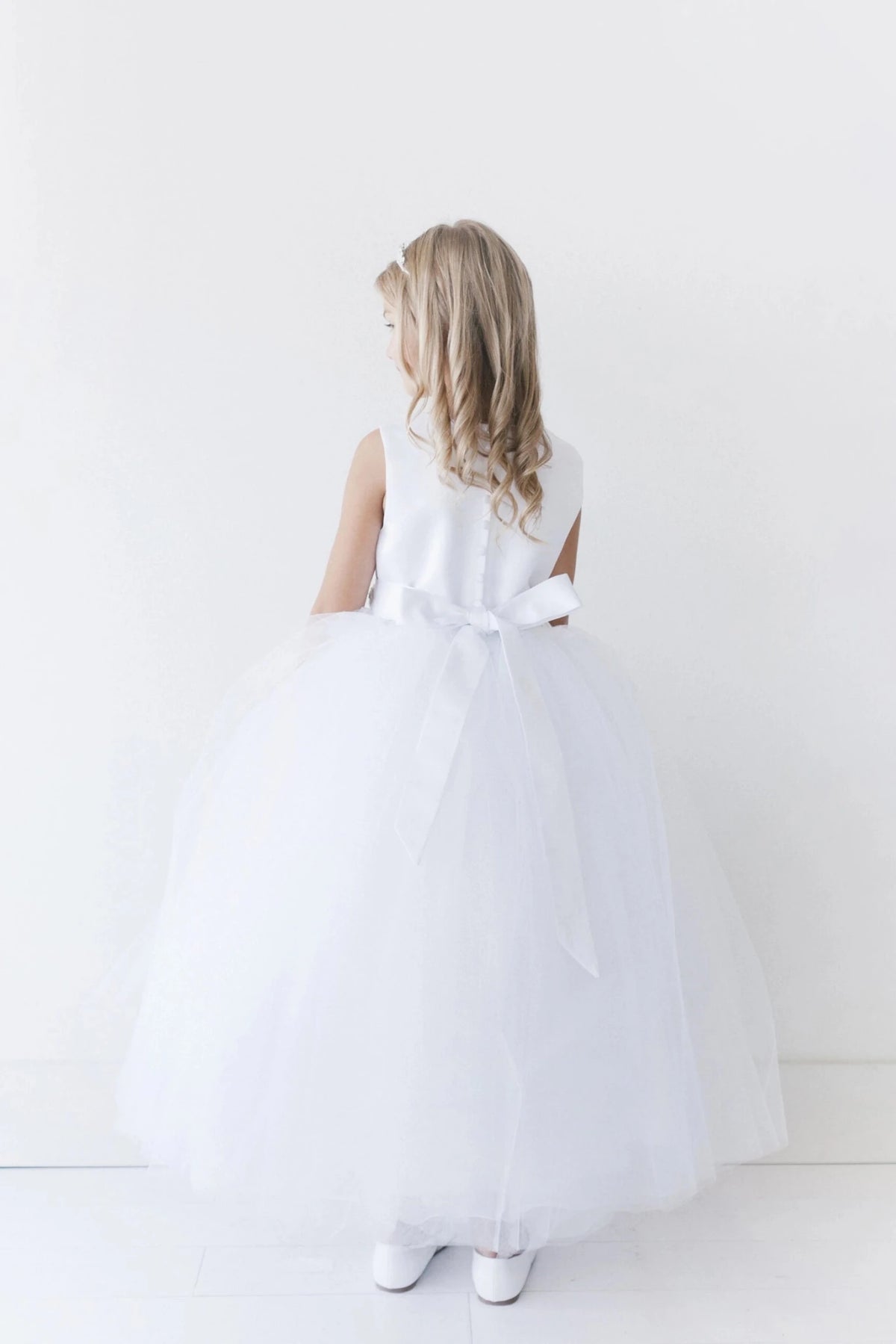 Long satin sash accents the white flower girl dress.