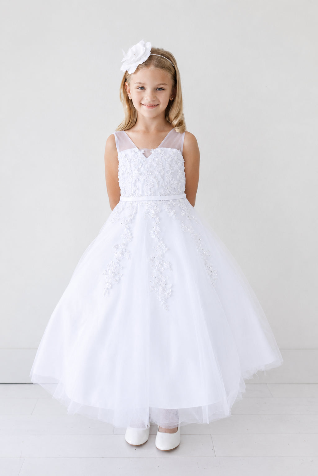 Meandering leafy embroidery decorates the white flower girl dress's skirt.