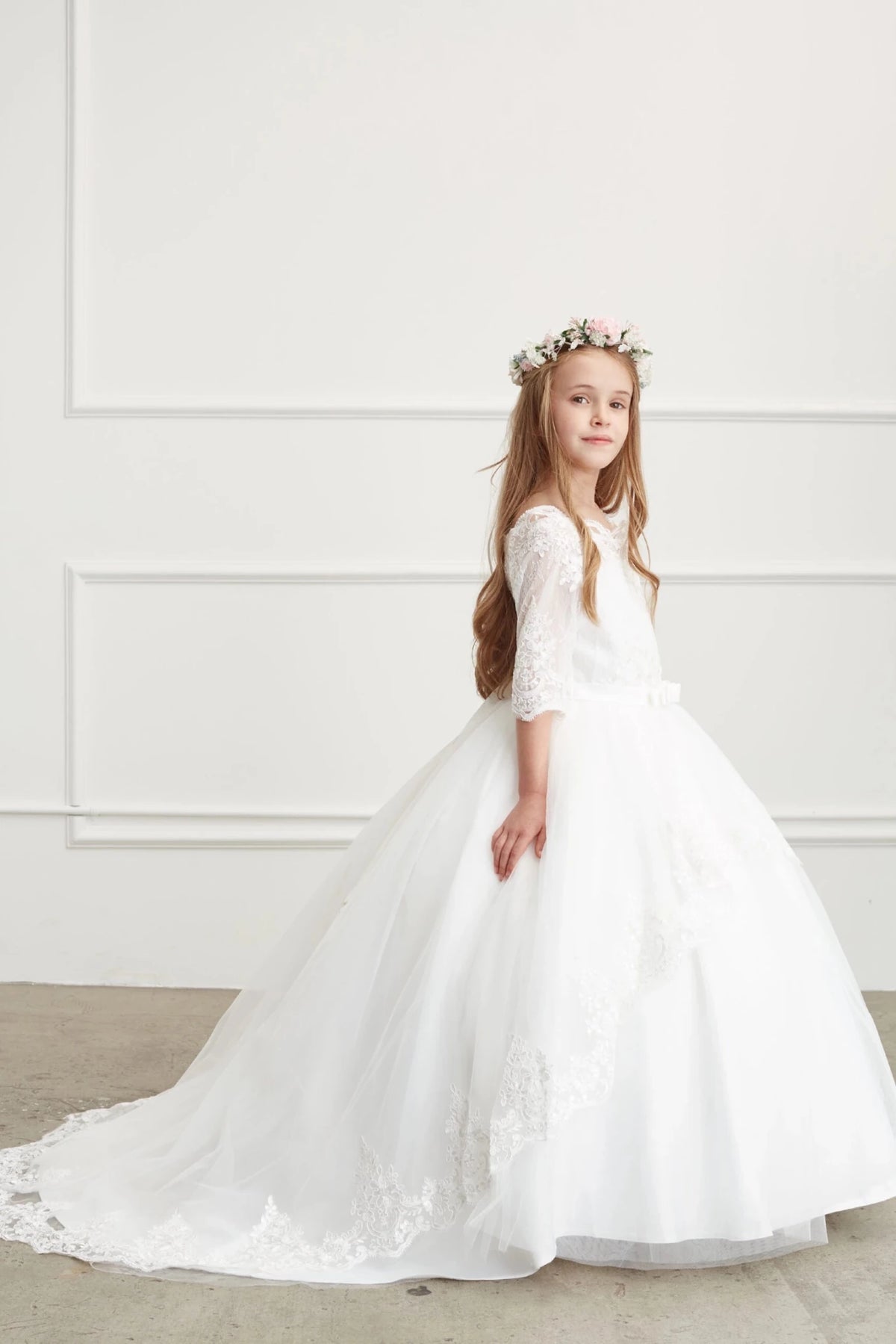 Lace-edged tulle trails behind the off-white flower girl dress.