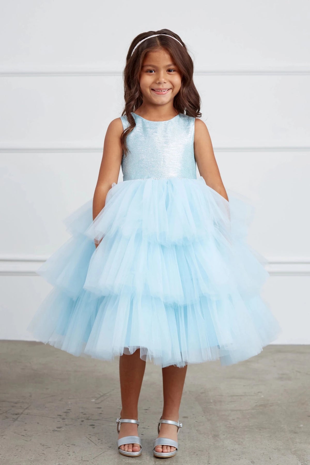 On this sky blue flower girl dress, a fluffy ruffled skirt is visible.