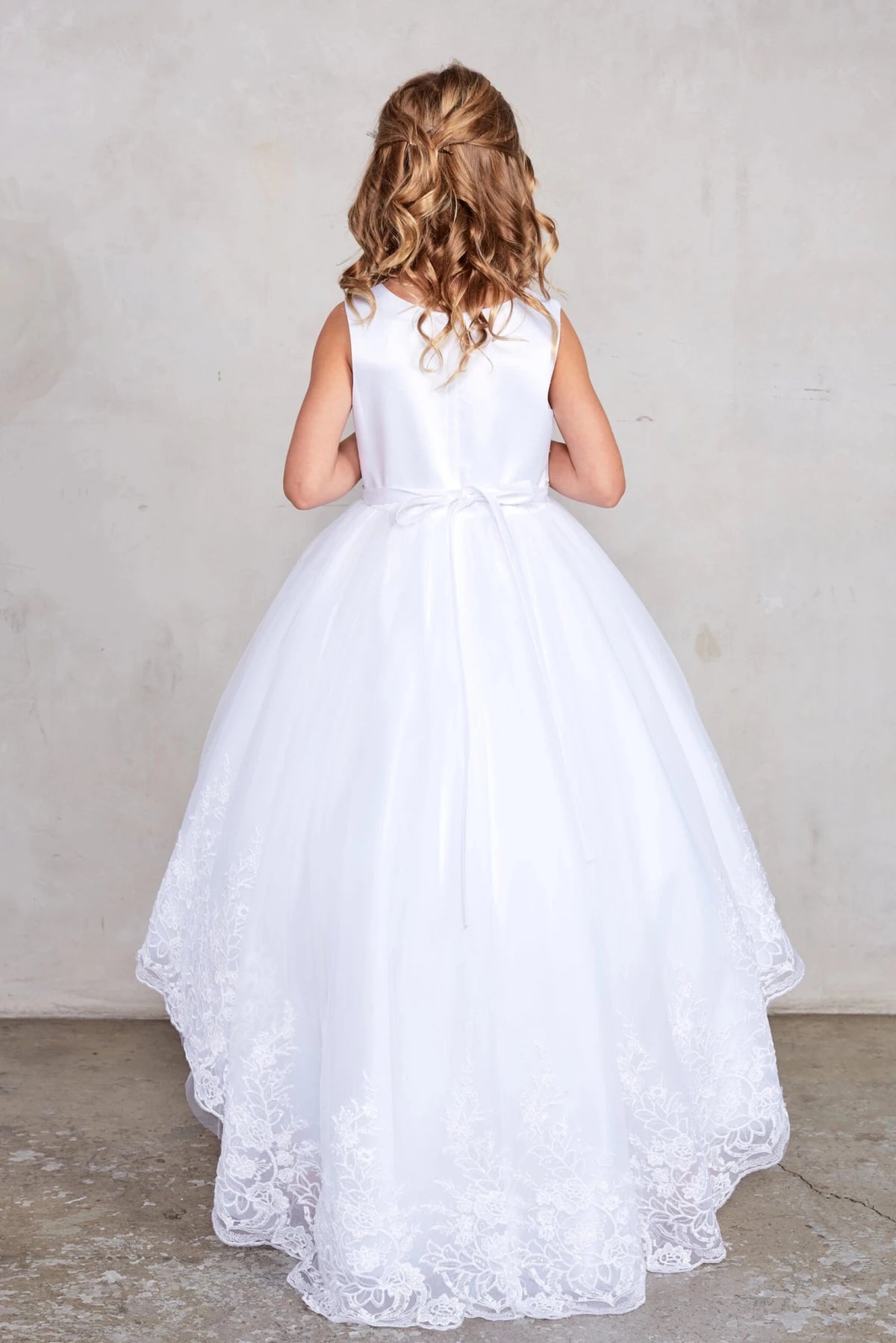 Tied back sash on a white flower girl dress.