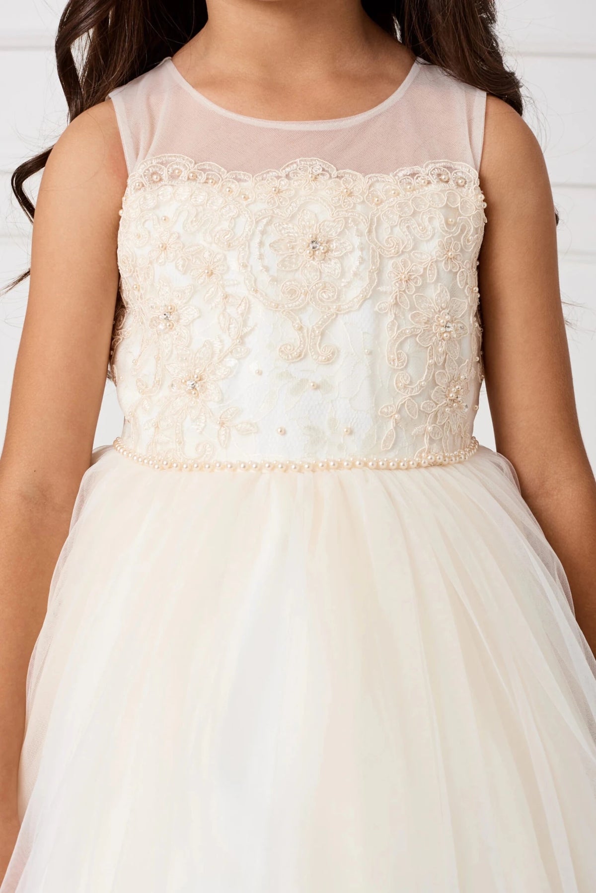 Beaded trim circles the champagne flower girl dress's waist.