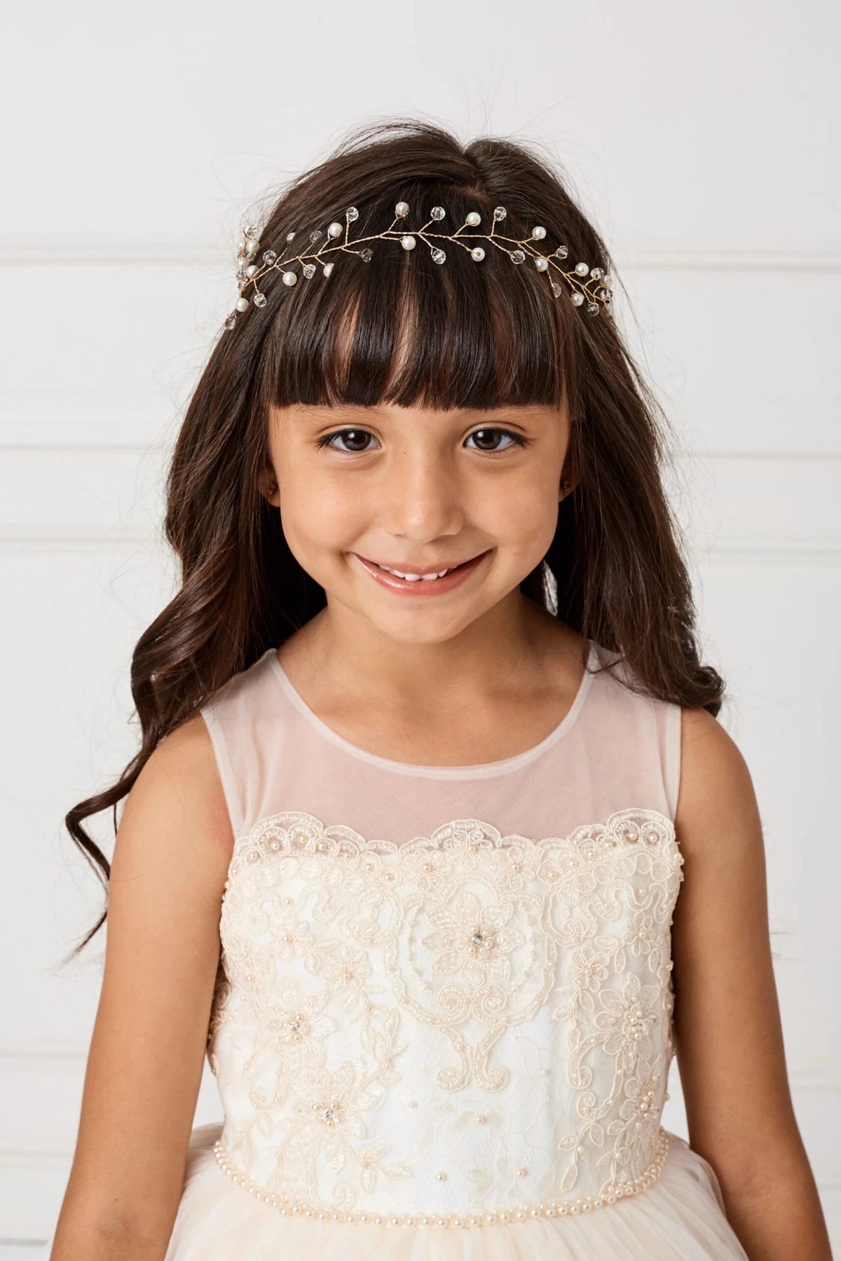 Over the sweetheart bodice, a champagne flower girl dress has a sheer yoke.