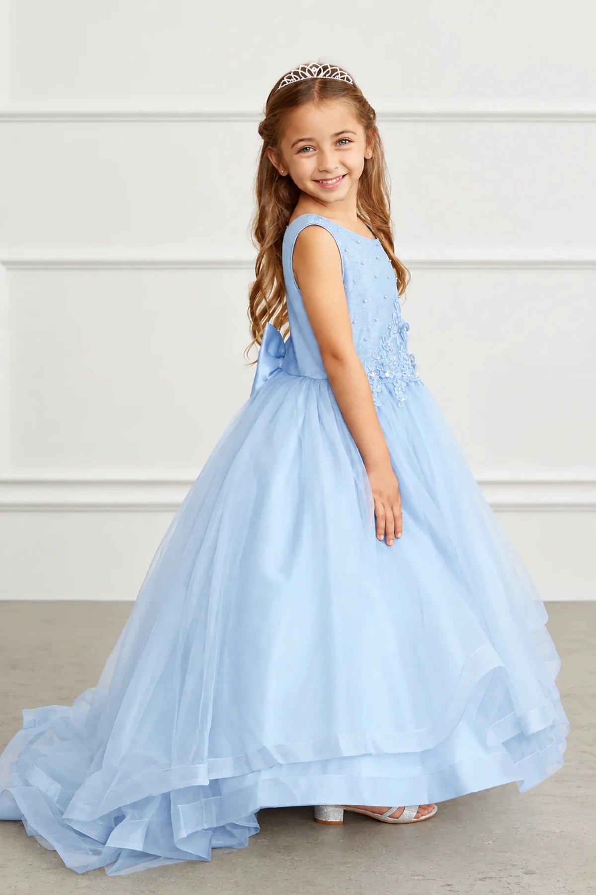 Skyblue flower girl dress showing broad bands along its layered hem.